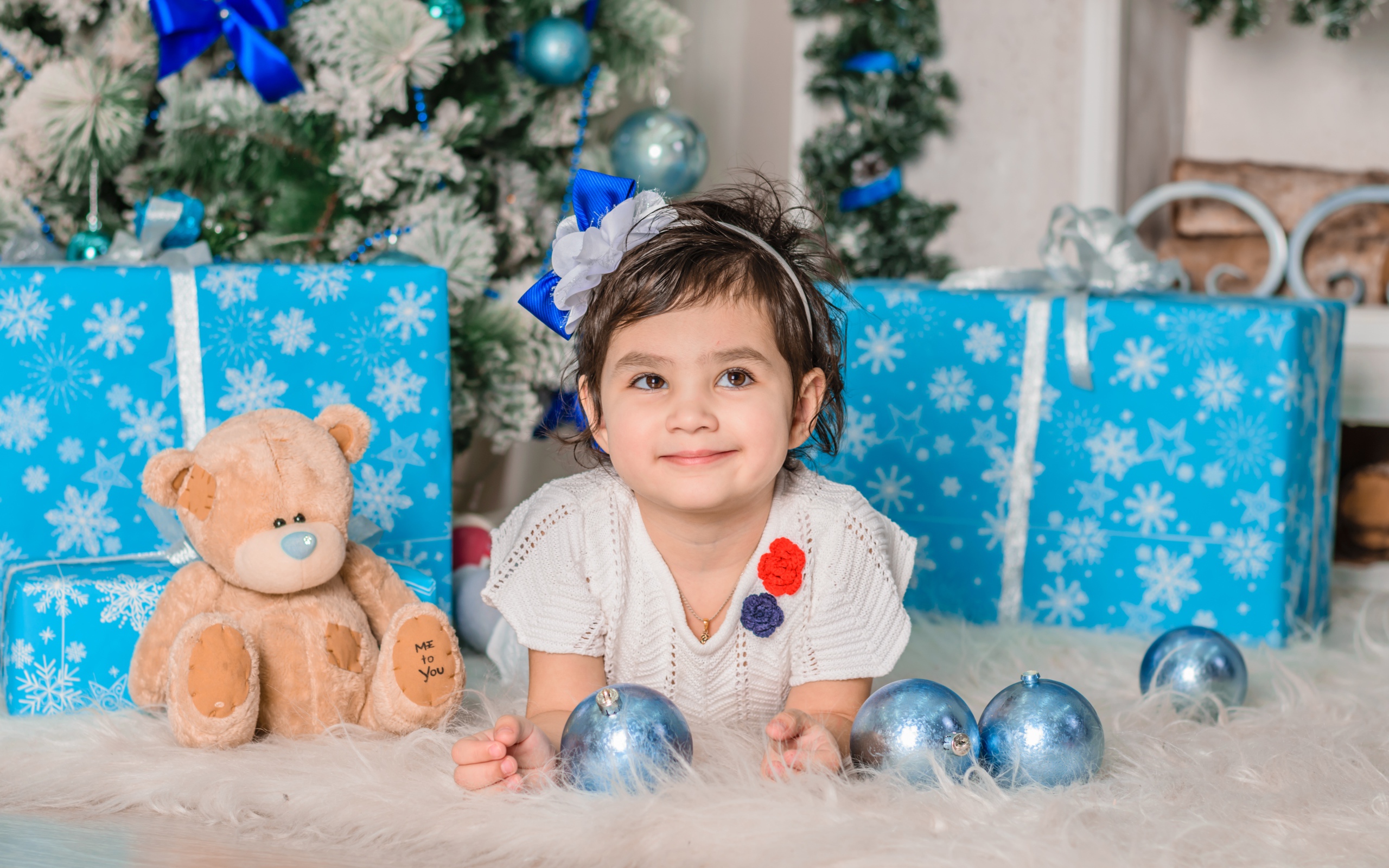 Маленькая девочка с подарками и игрушками под елкой 