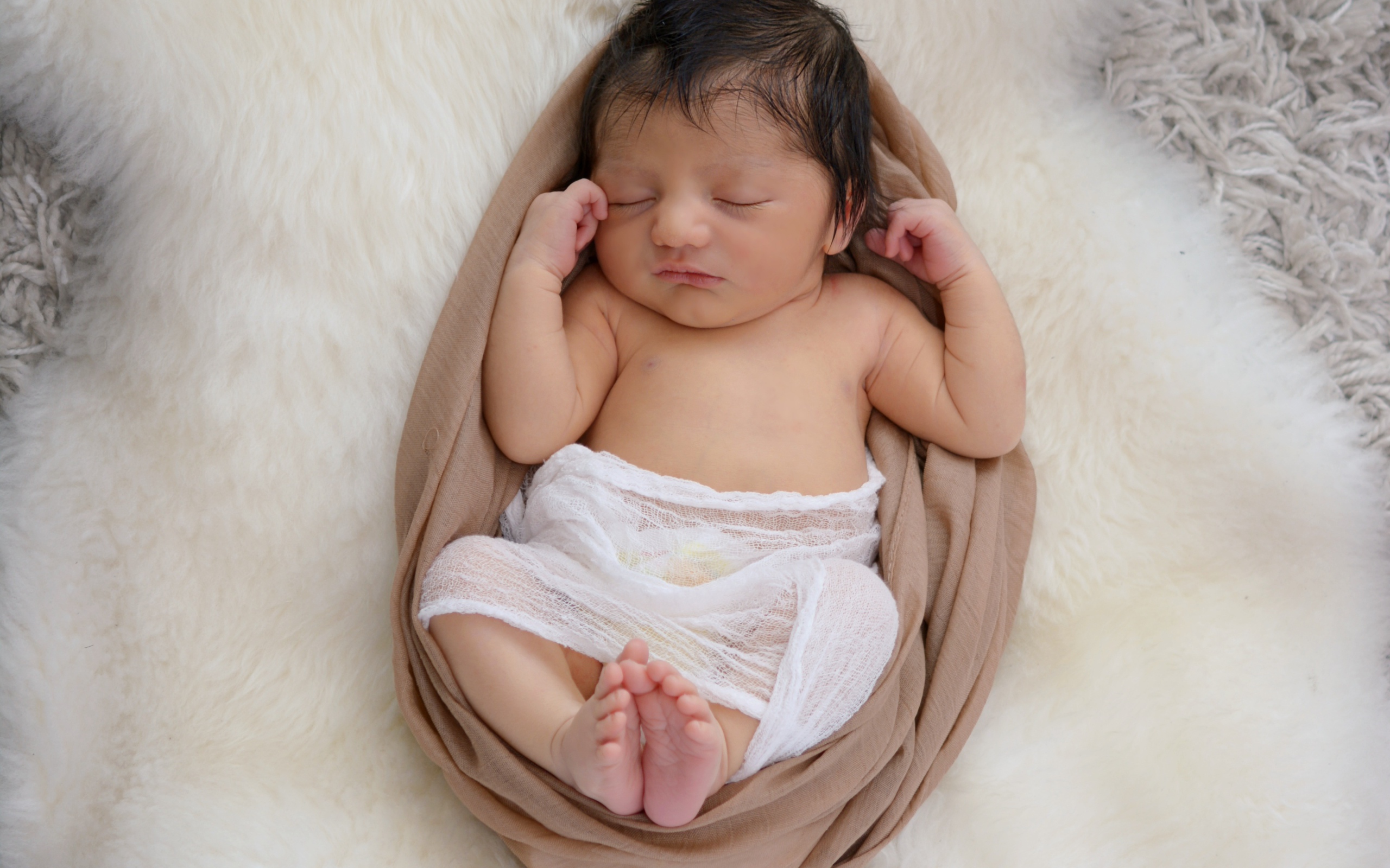 Спящий грудной ребенок на меховом покрывале 