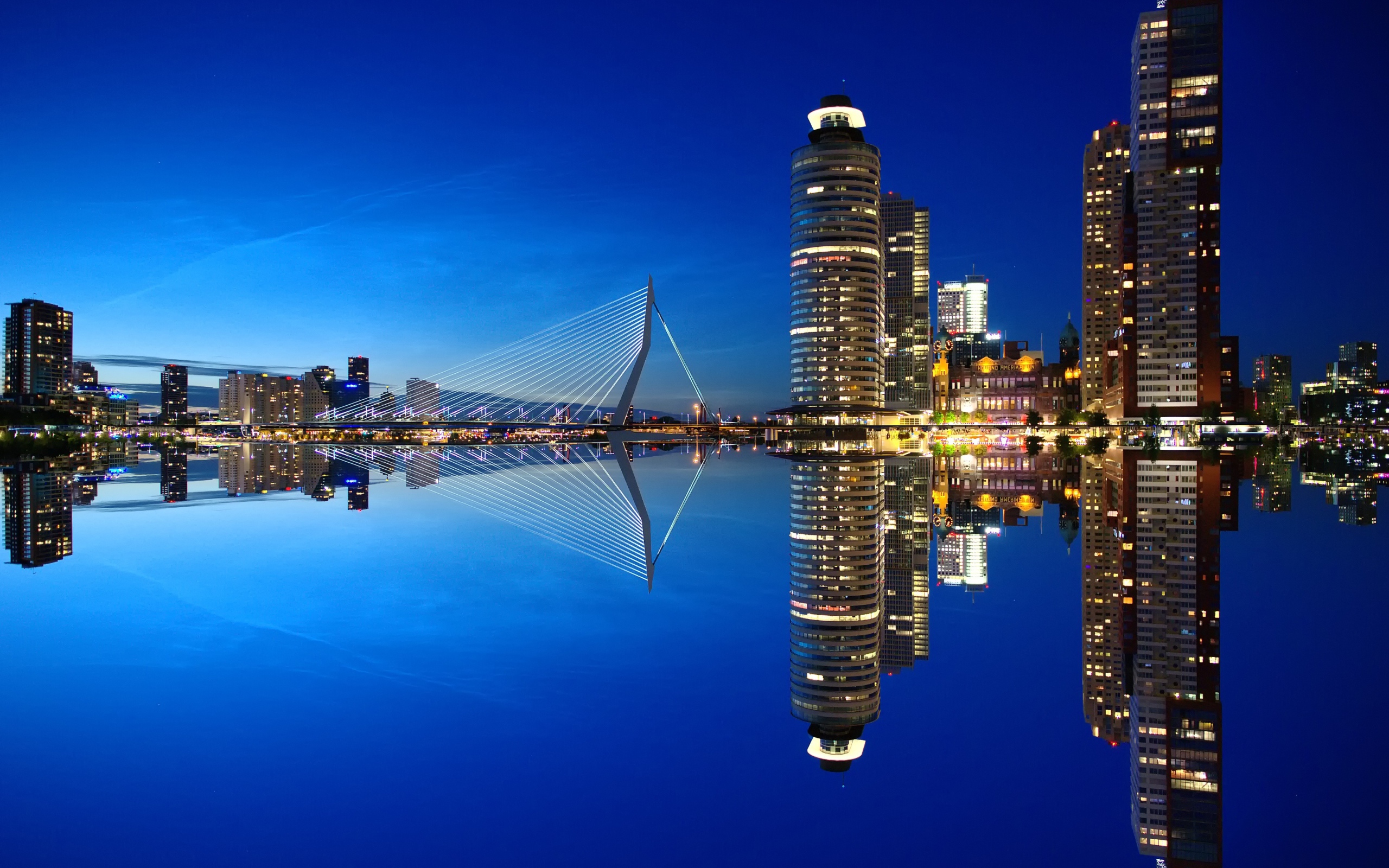 Небоскребы и мост отражаются в тихой воде