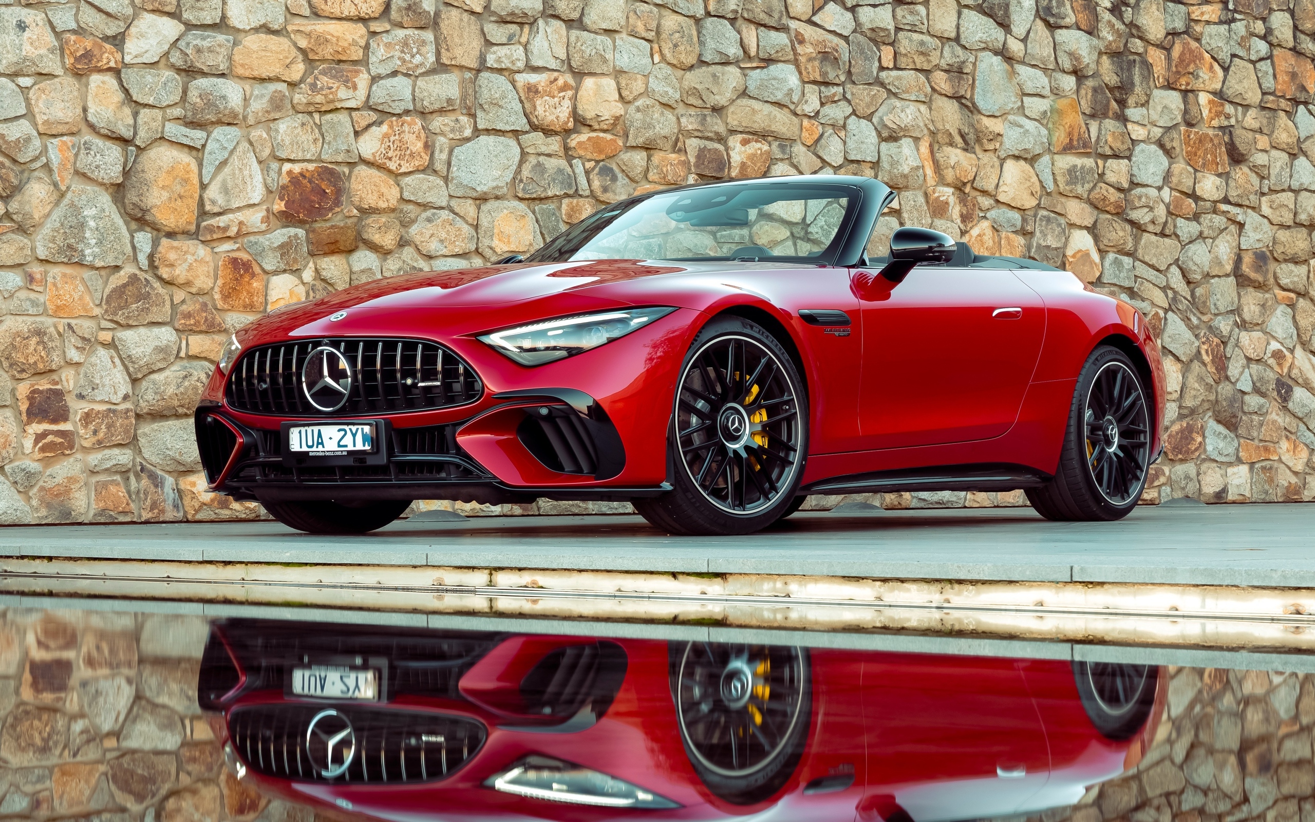 Красный Mercedes-AMG SL 63 4MATIC+ 2023 года на фоне стены