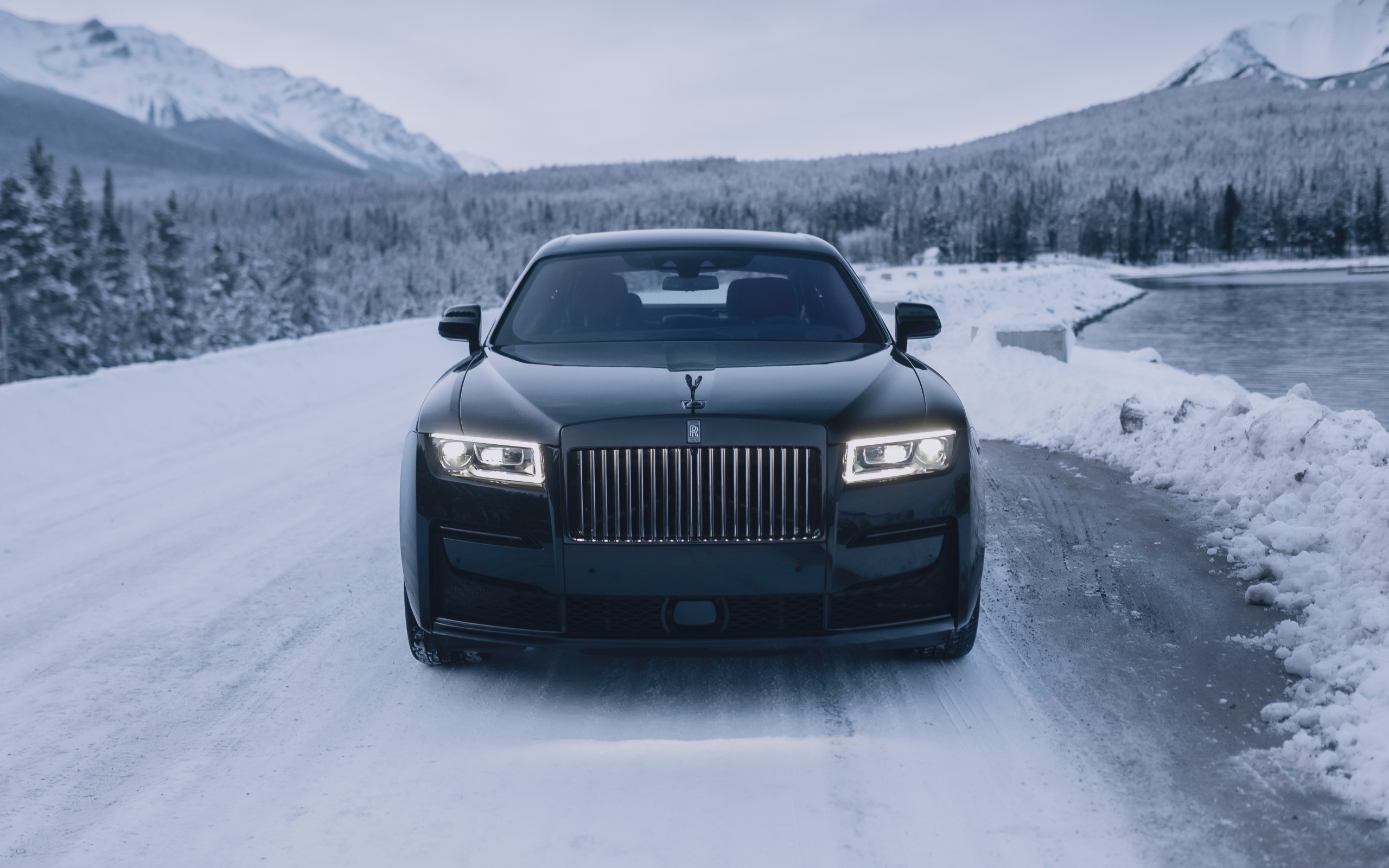 Черный автомобиль Rolls-Royce Black Badge Ghost  на зимней дороге
