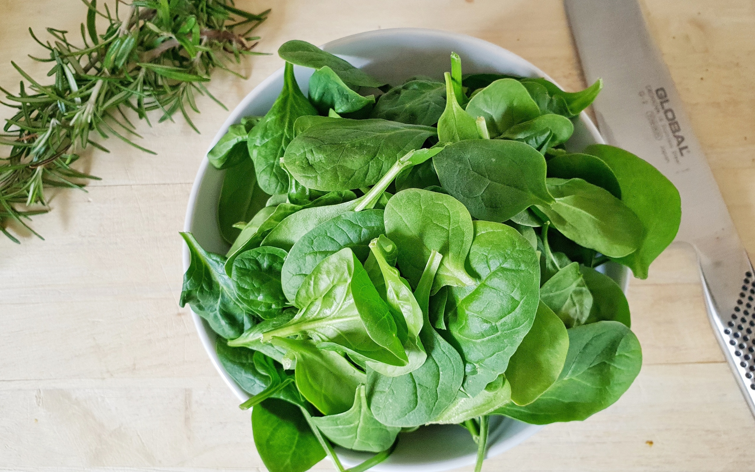 Зеленые листья базилика на столе с розмарином