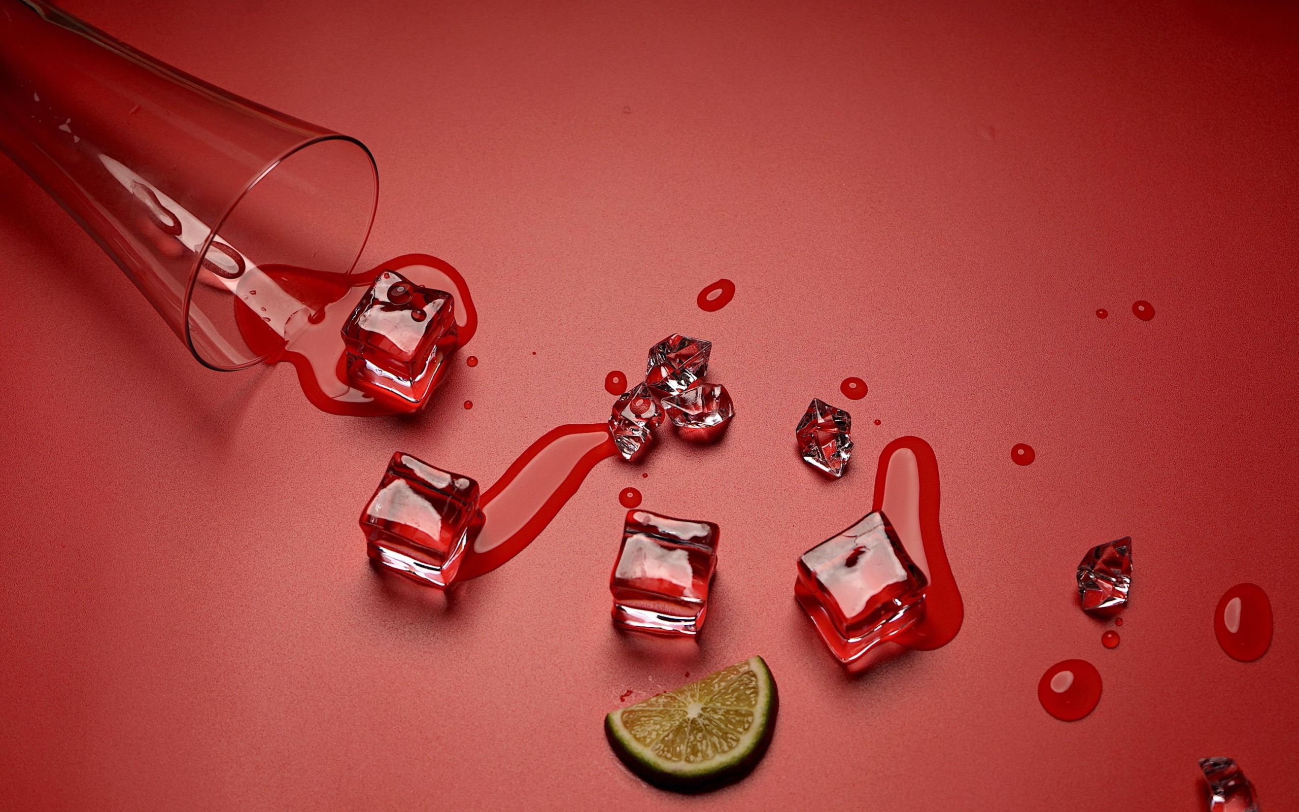 Кубики льда на красном фоне с кусочком лайма и стаканом