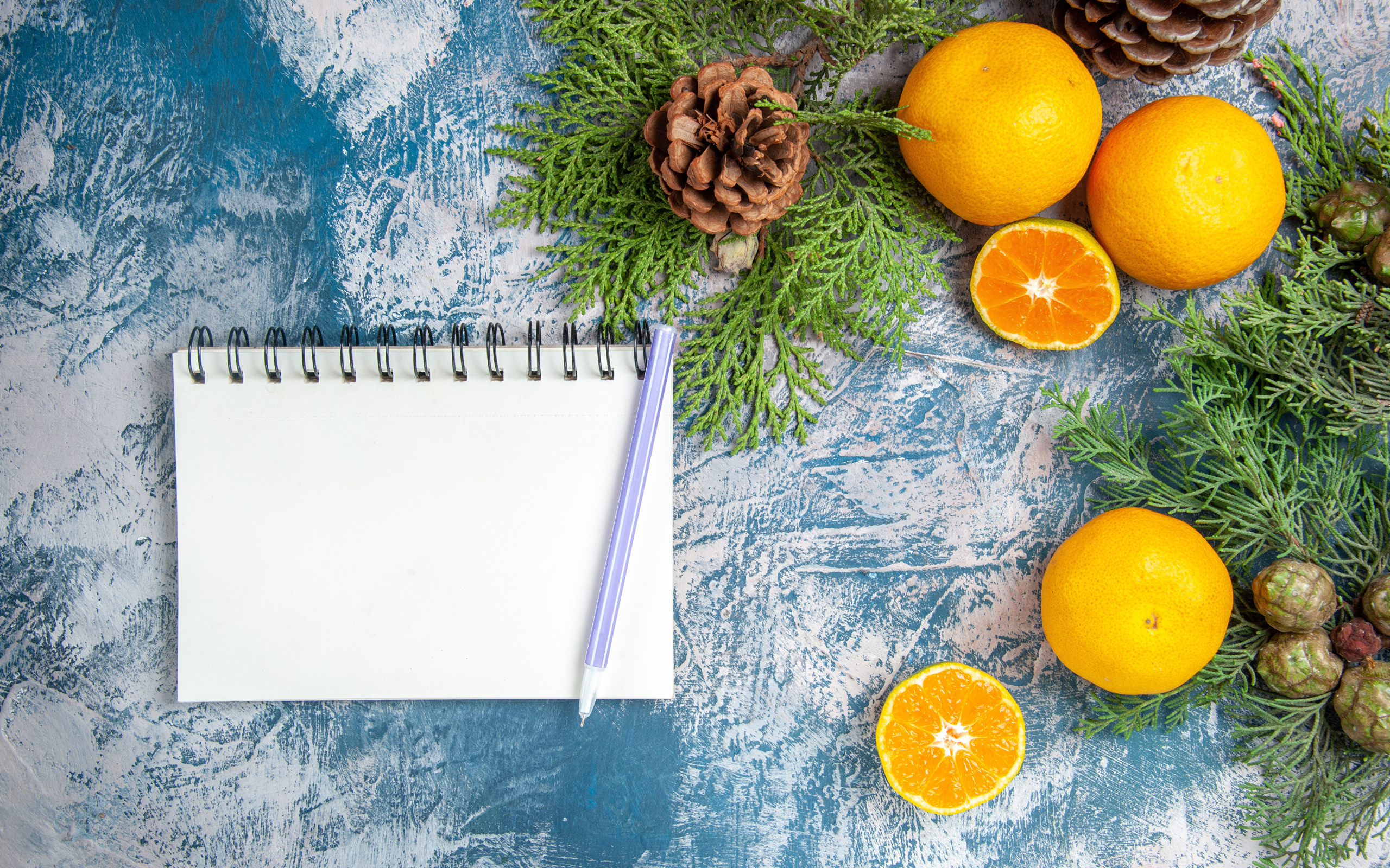 Блокнот на столе с мандаринами и ветками