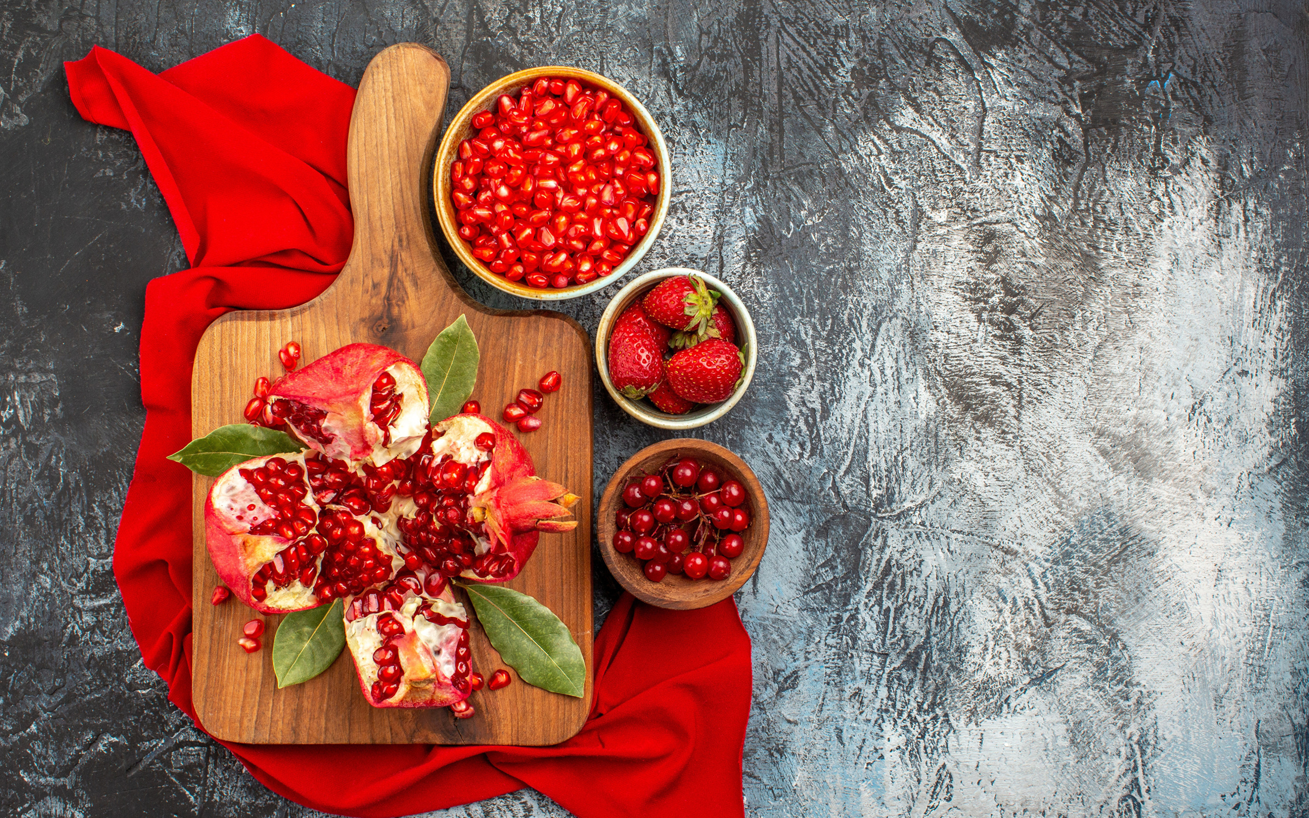 Очищенный гранат на столе с клубникой и ягодами смородины