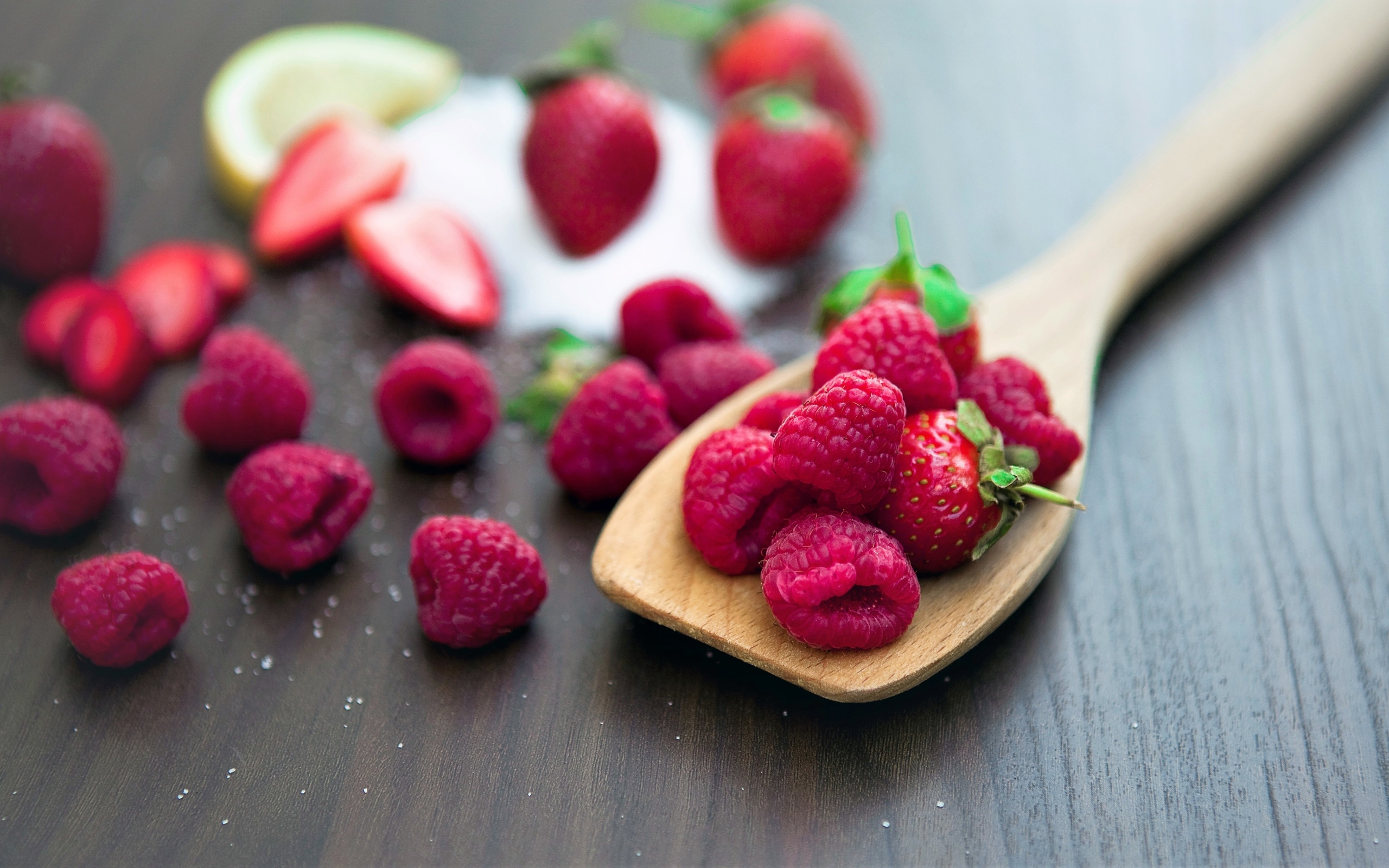 Спелая красная малина с деревянной ложкой на столе