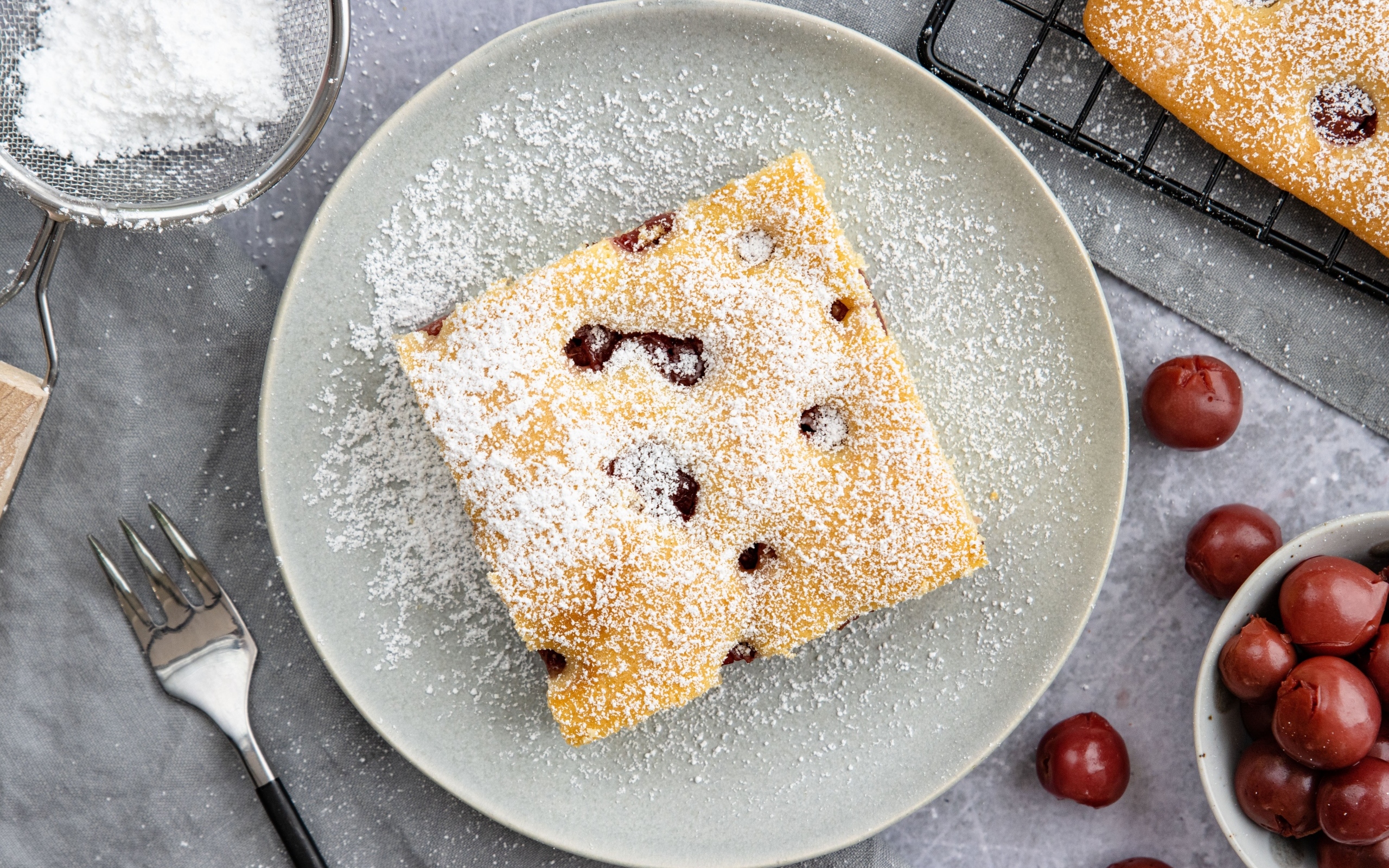 Кусок вишневого пирога на тарелке с сахарной пудрой