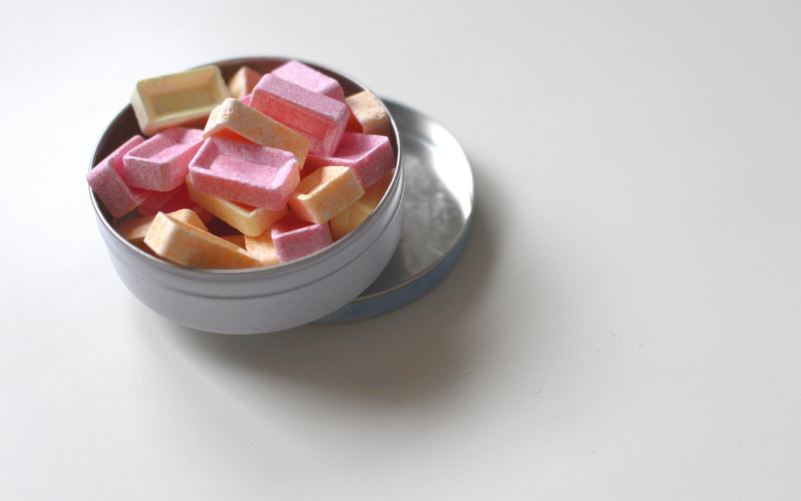 Розовые и оранжевые конфеты в коробке на сером фоне