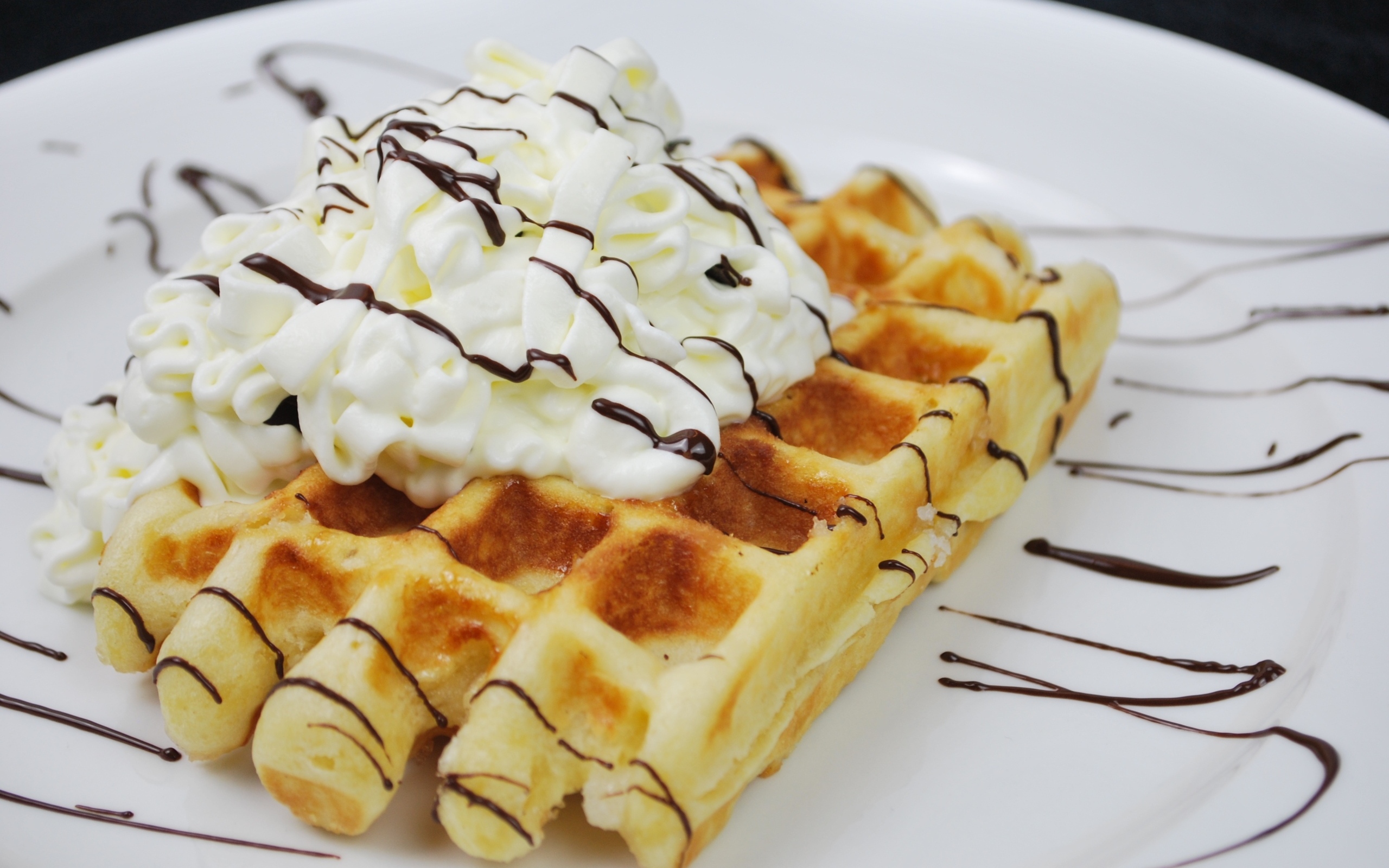 Сладкая вафля со сливками на белой тарелке