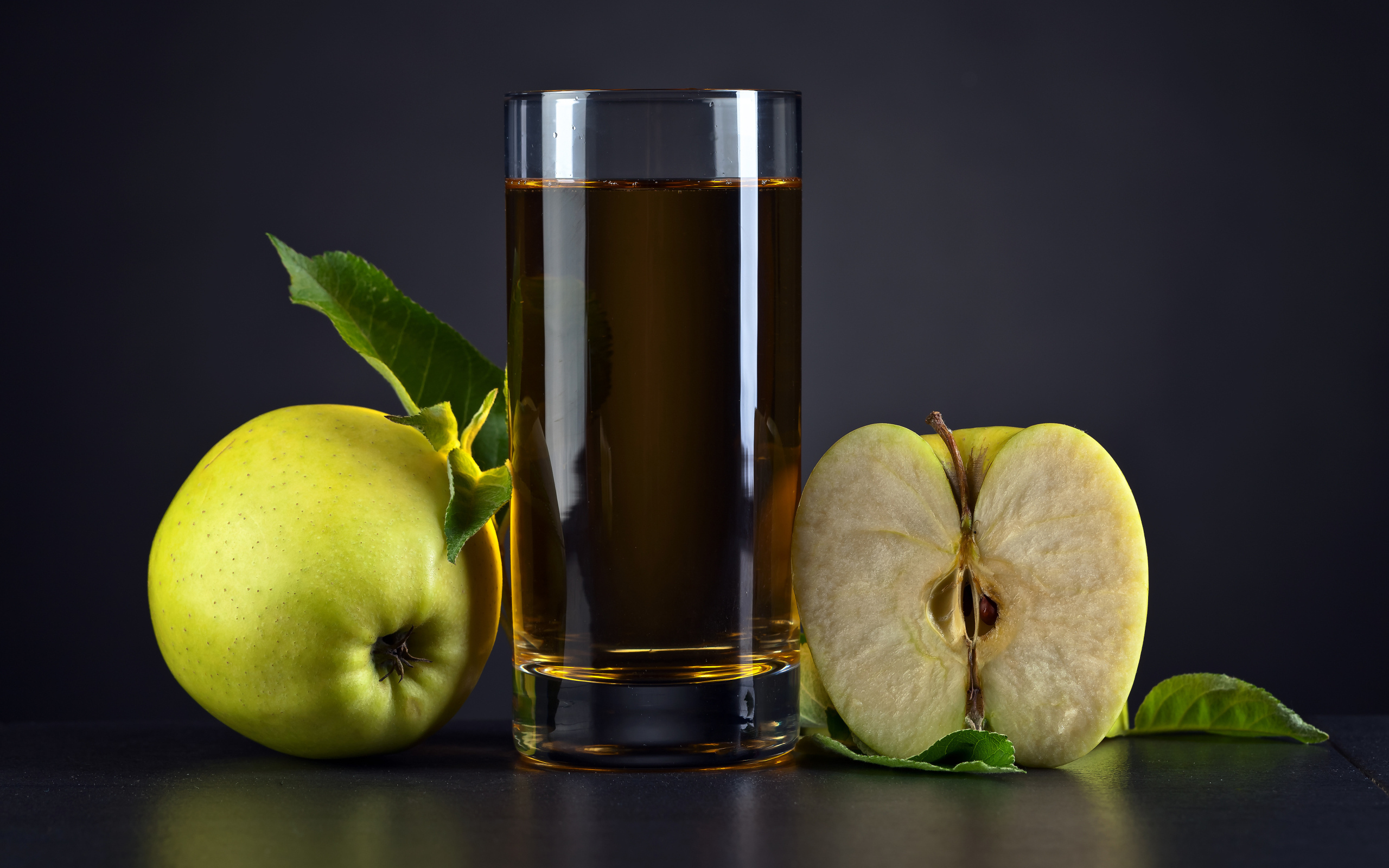 Стакан сока с зелеными яблоками на сером столе
