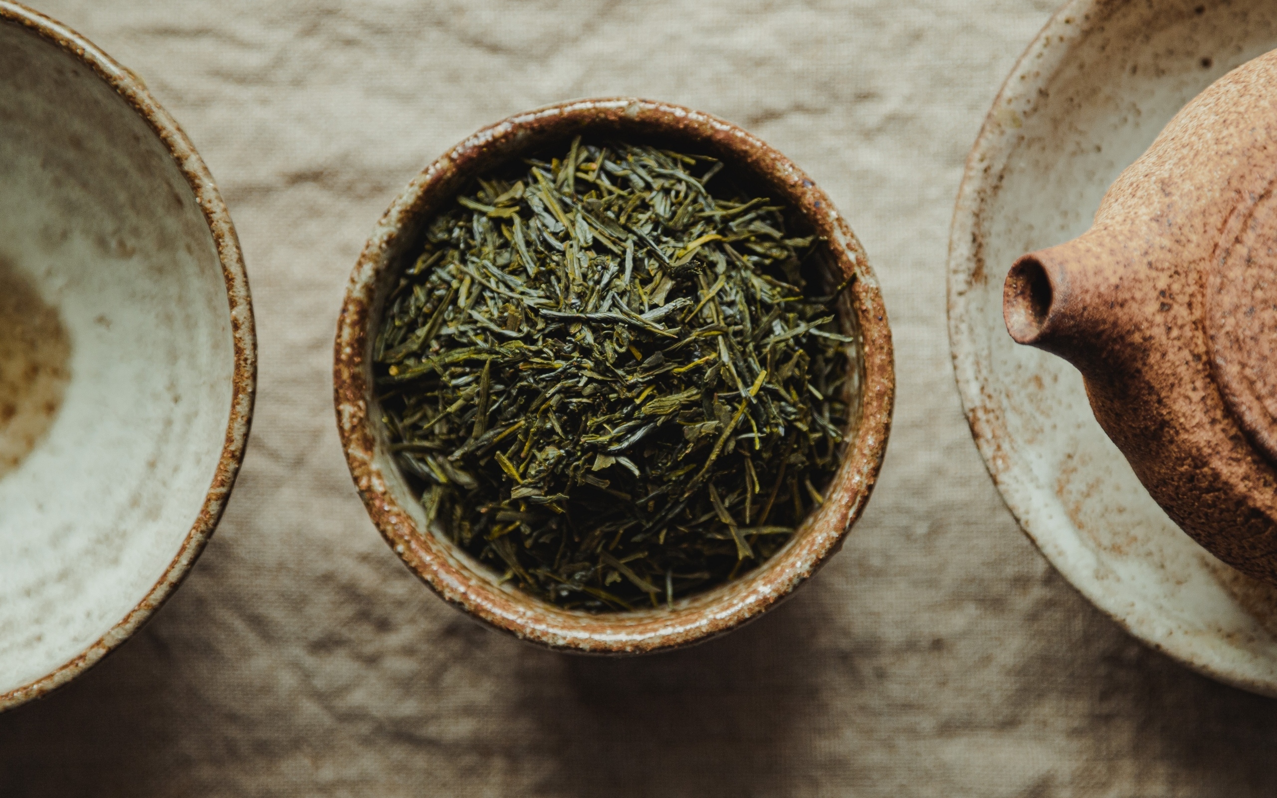 Зеленый чай в пиале на столе с чайником