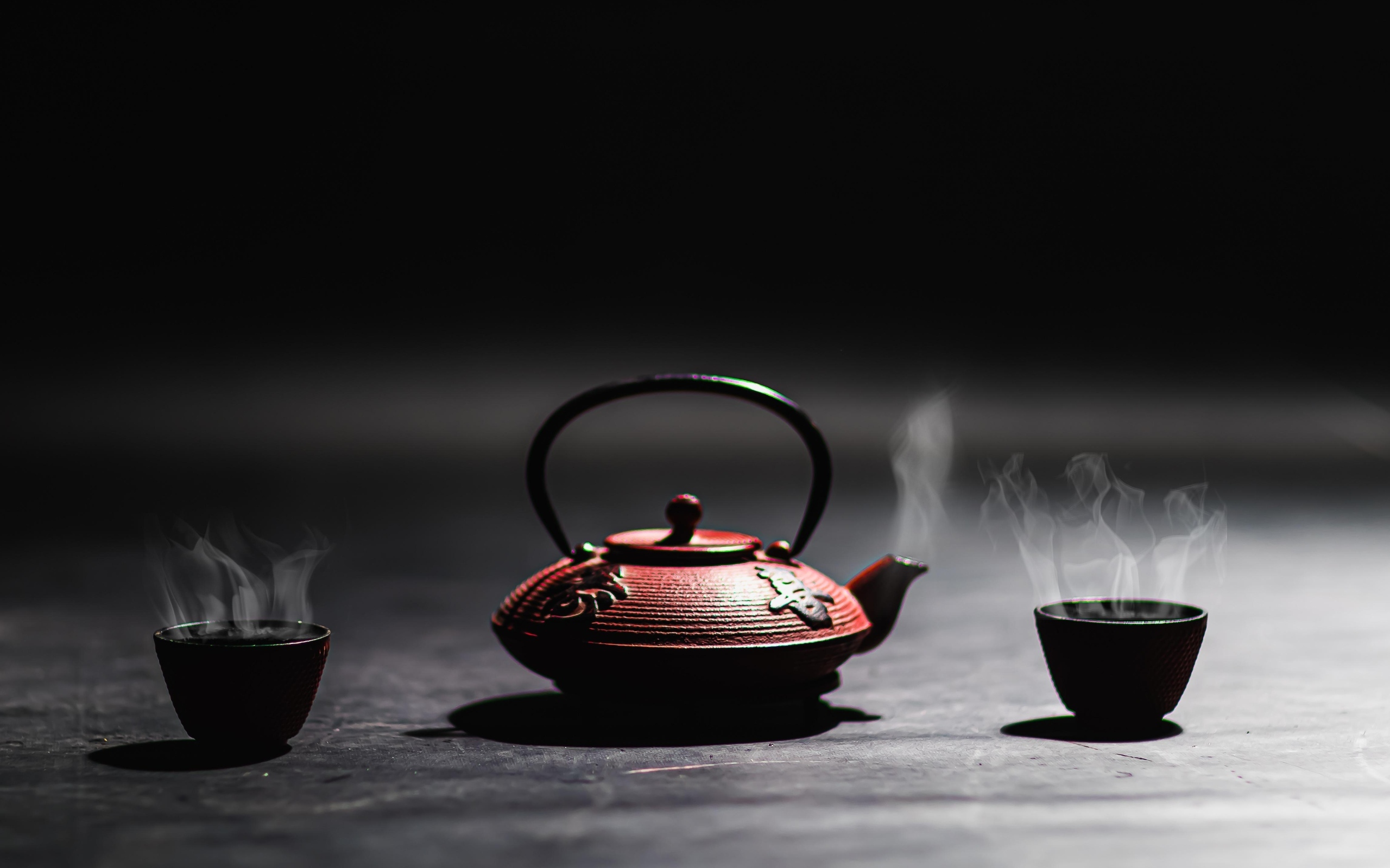 Чайник с горячим чаем на черном фоне