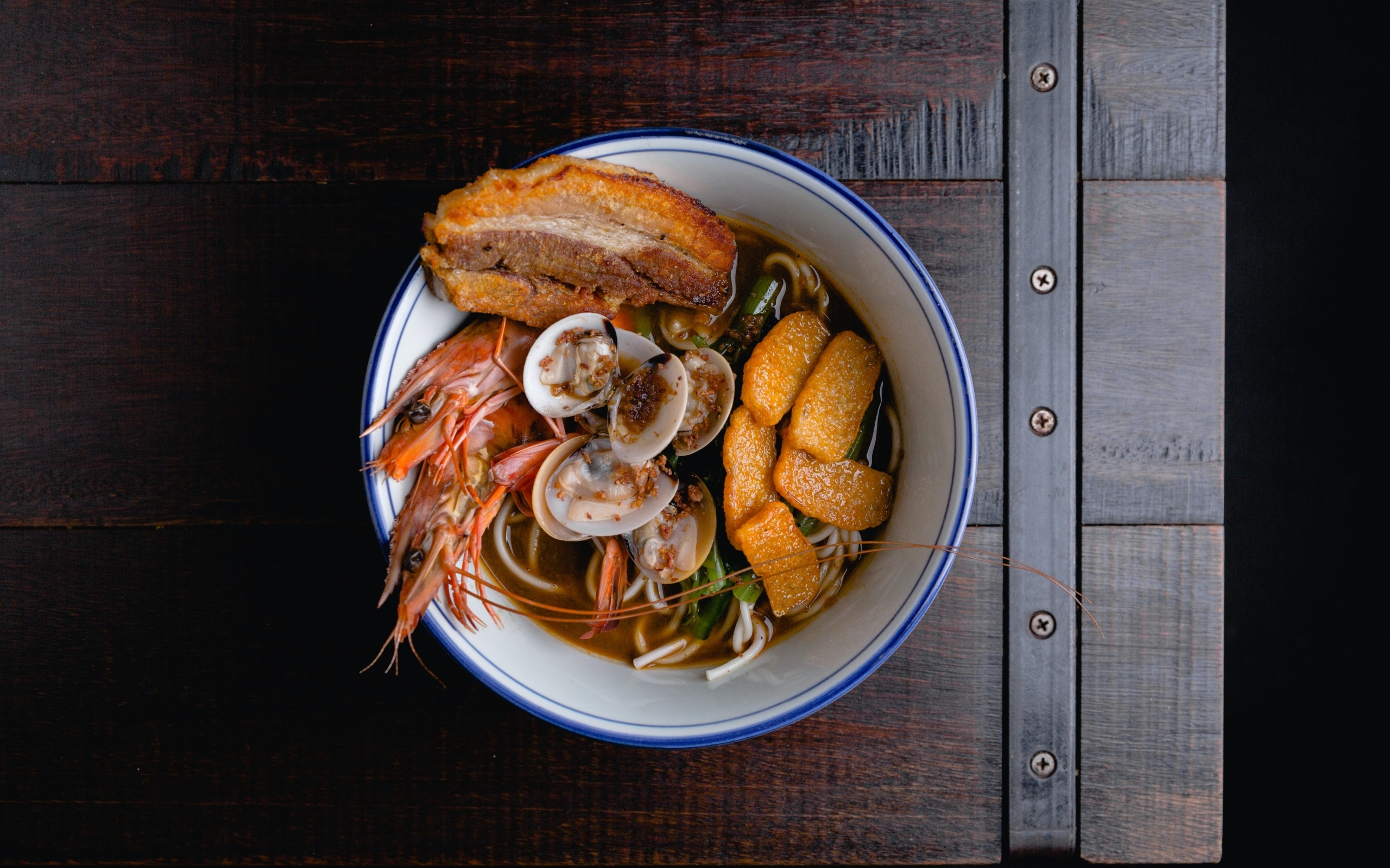 Суп с лапшой и морепродуктами на деревянном столе