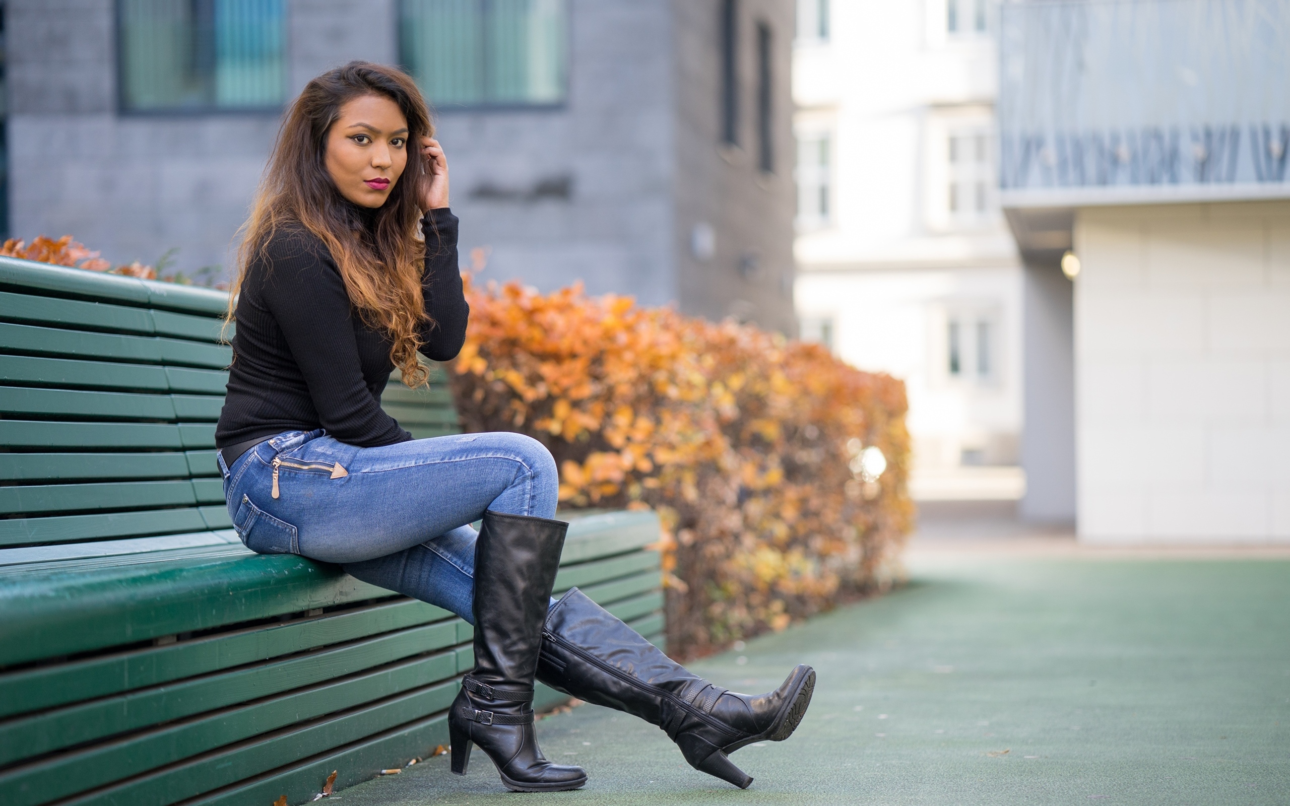 Брюнетка в синих джинсах сидит на лавке