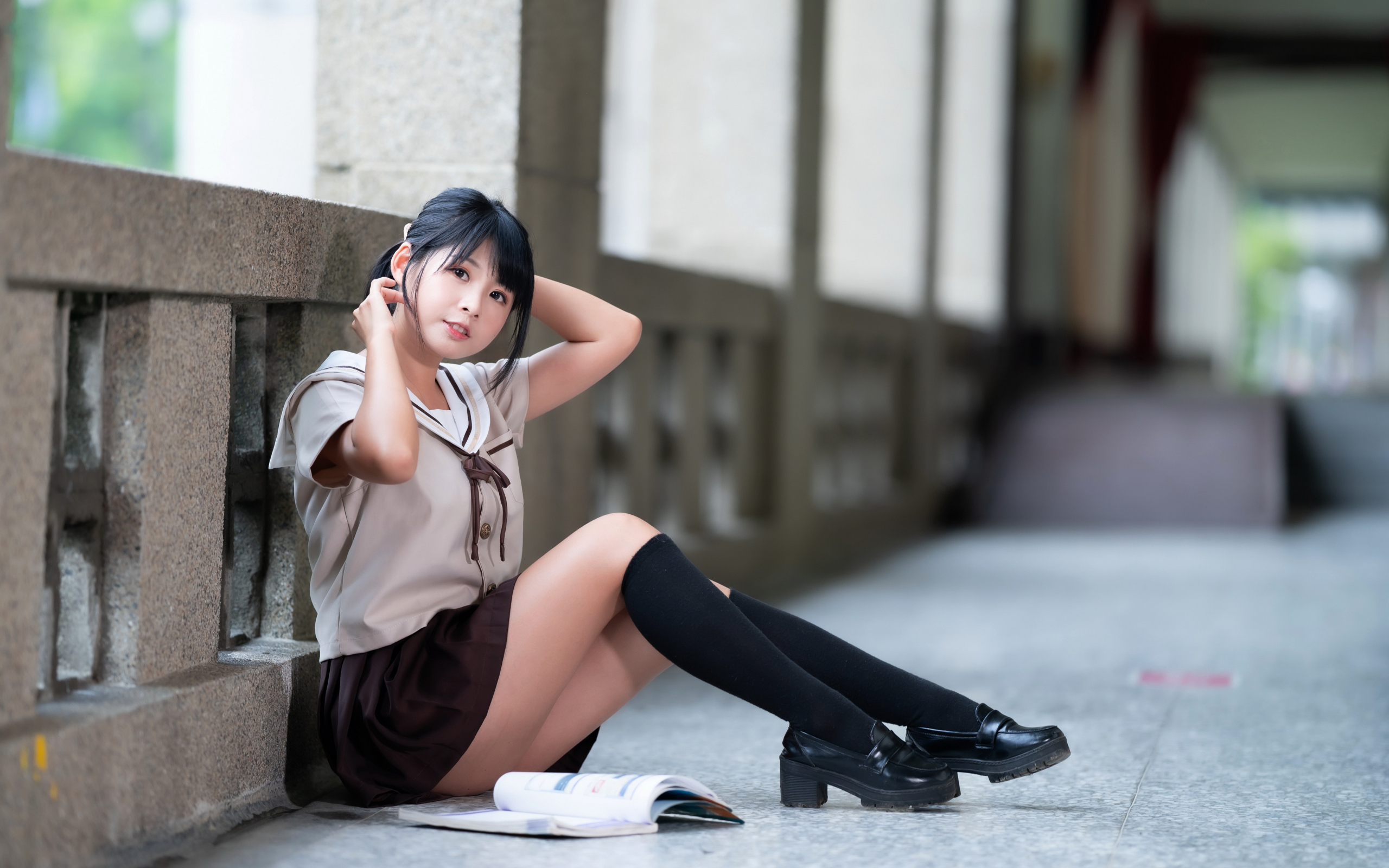 Девушка азиатка в школьной форме сидит на полу