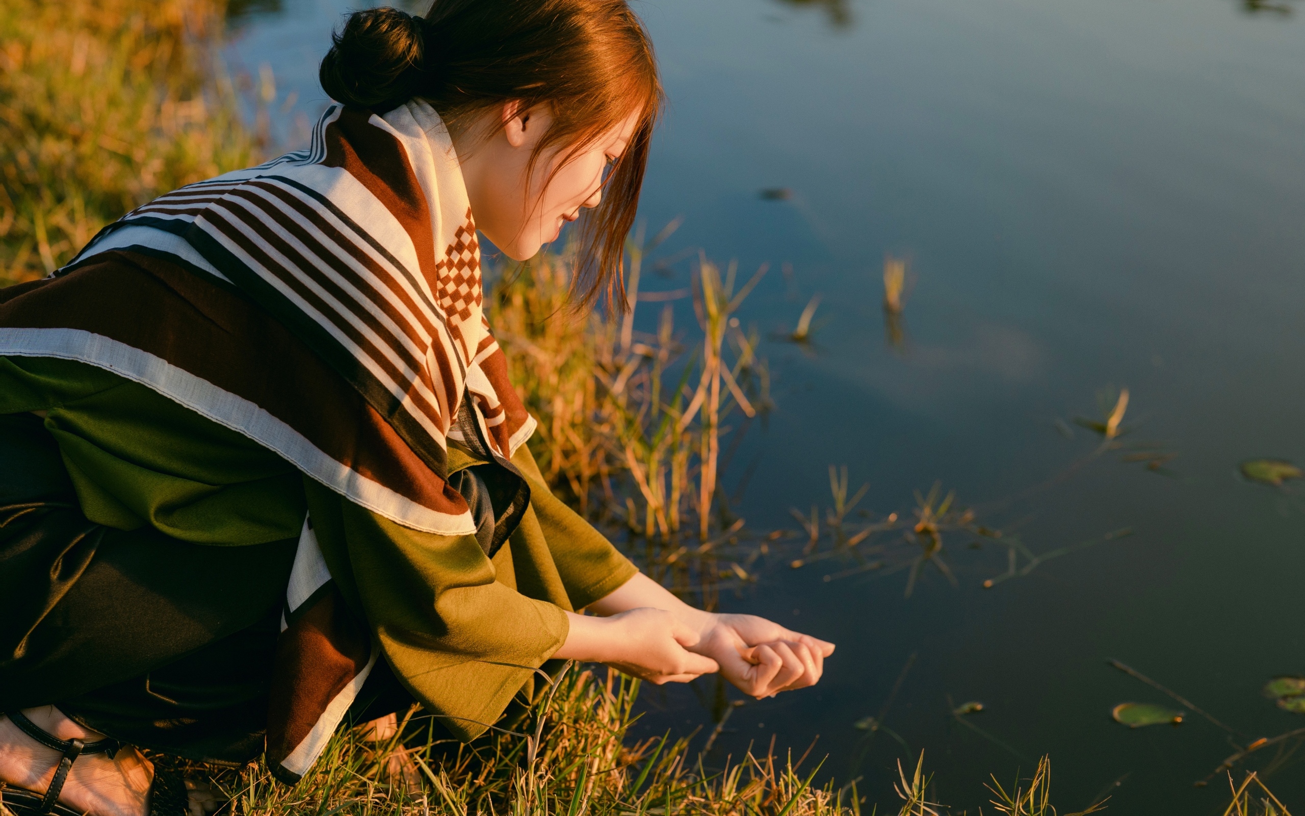 Девушка азиатка сидит у пруда