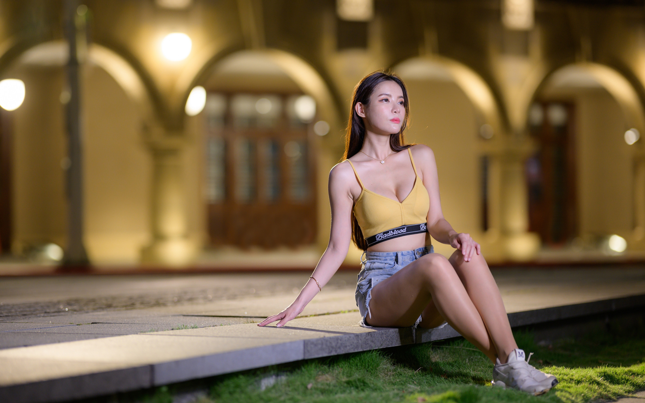 Девушка азиатка сидит на бетонной плите у дома