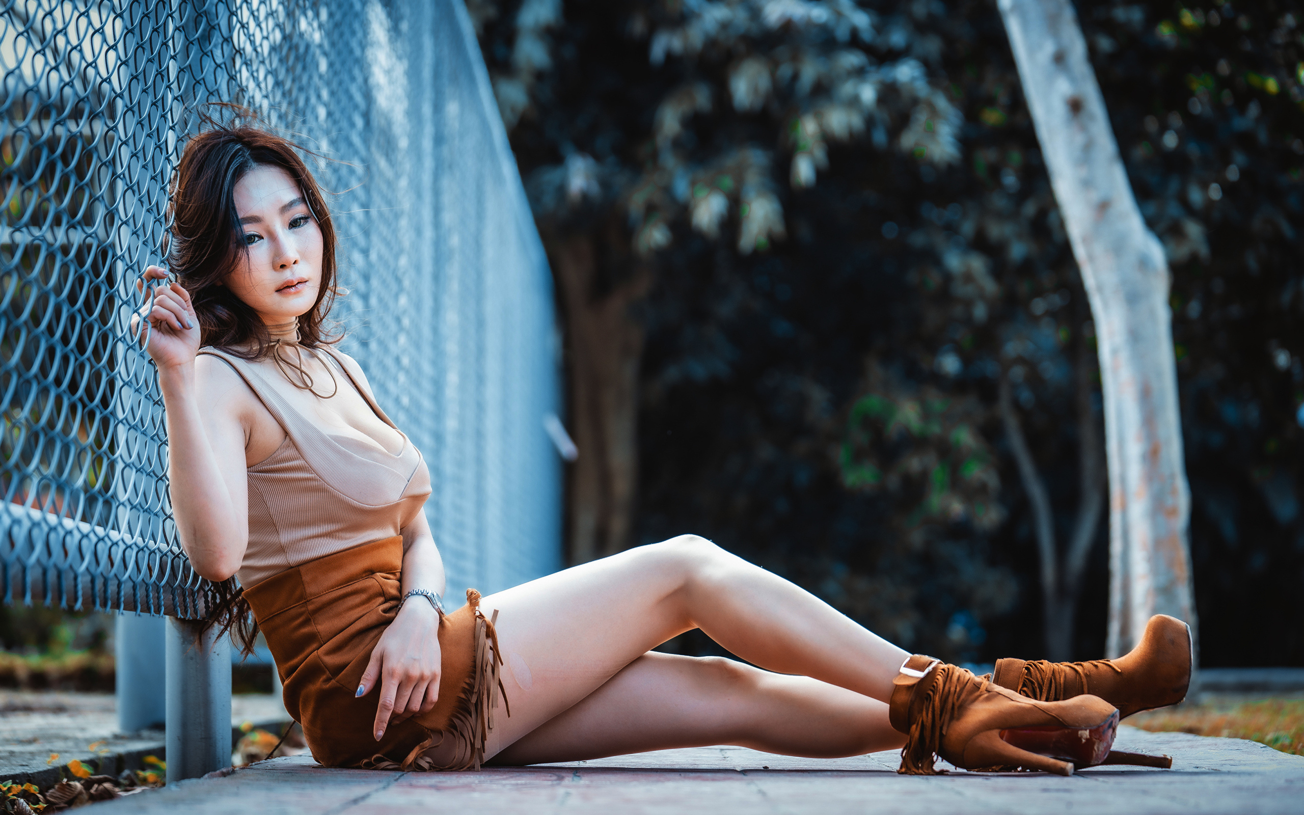 Девушка азиатка сидит на земле у сетки