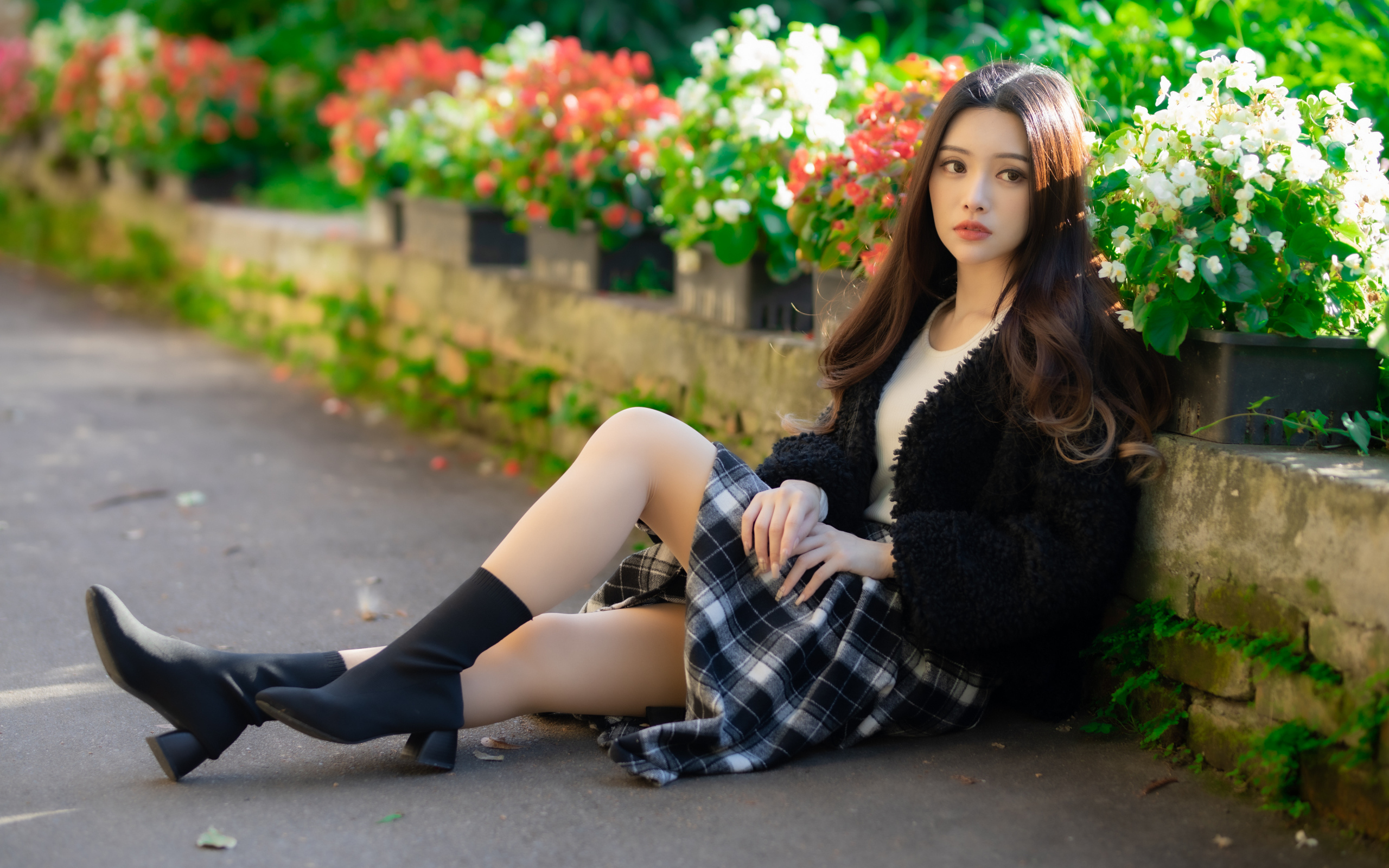 Азиатка сидит на асфальте у цветов