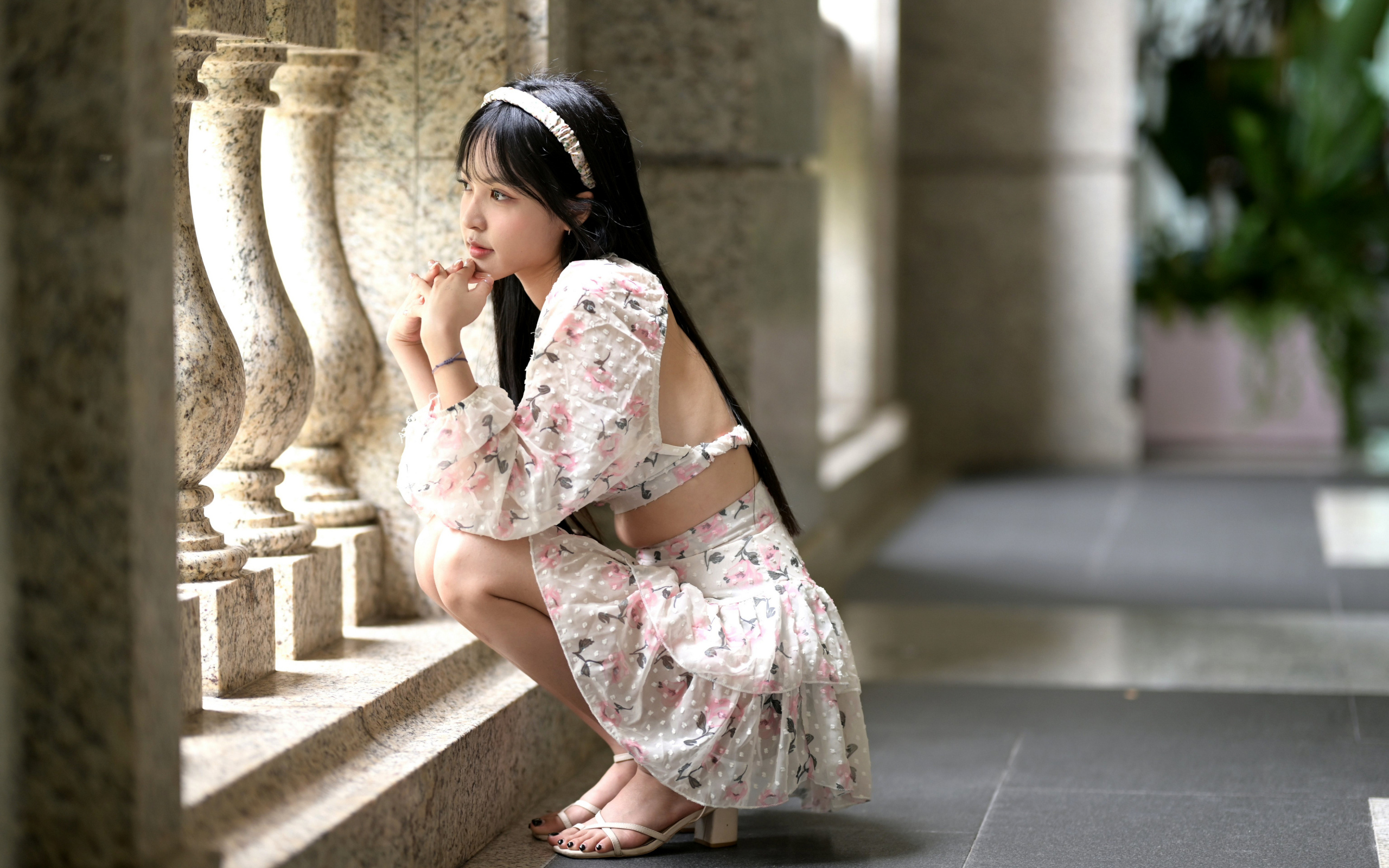 Красивая девушка азиатка в костюме сидит у стены