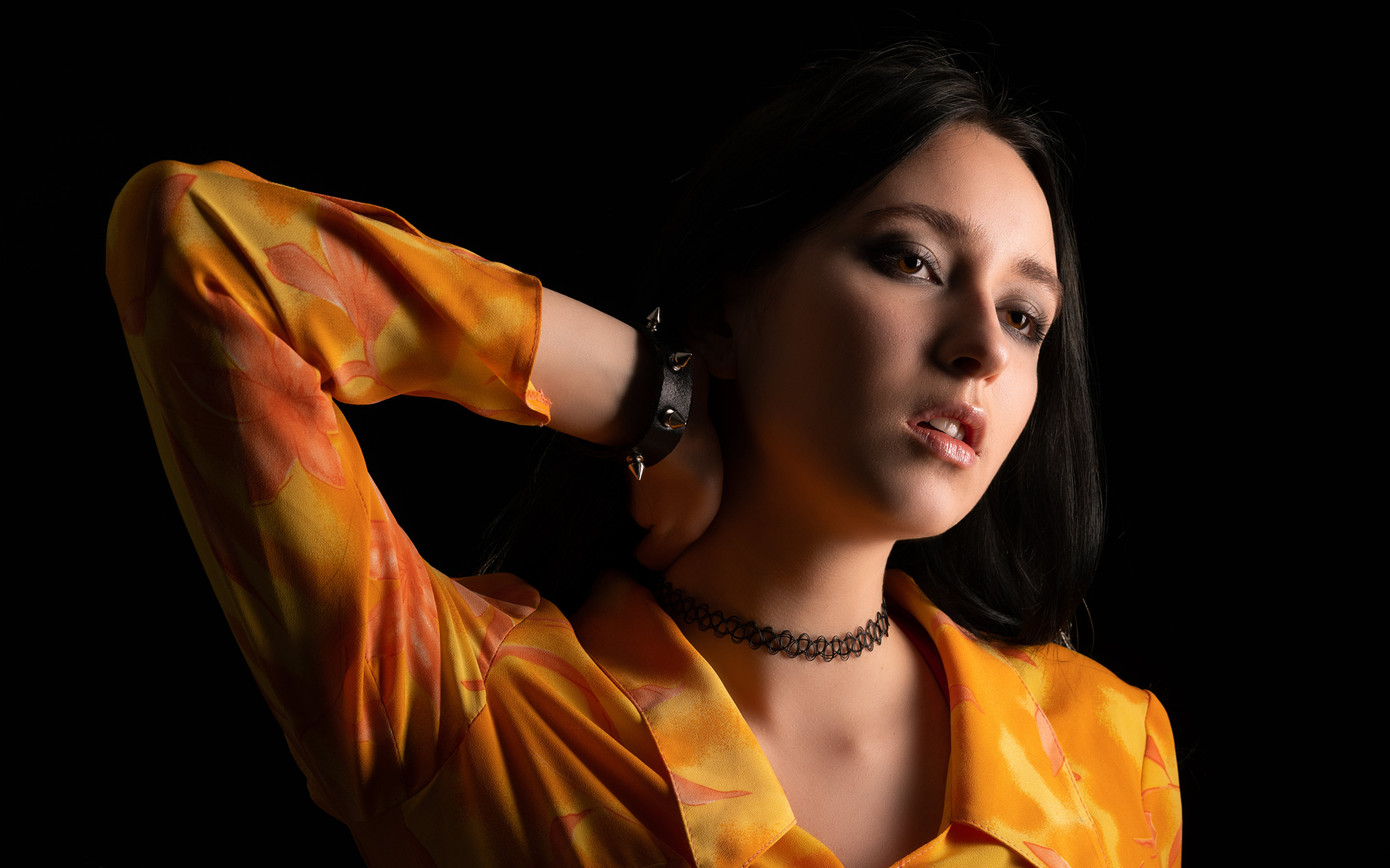 Красивая девушка шатенка с рукой в волосах на черном фоне