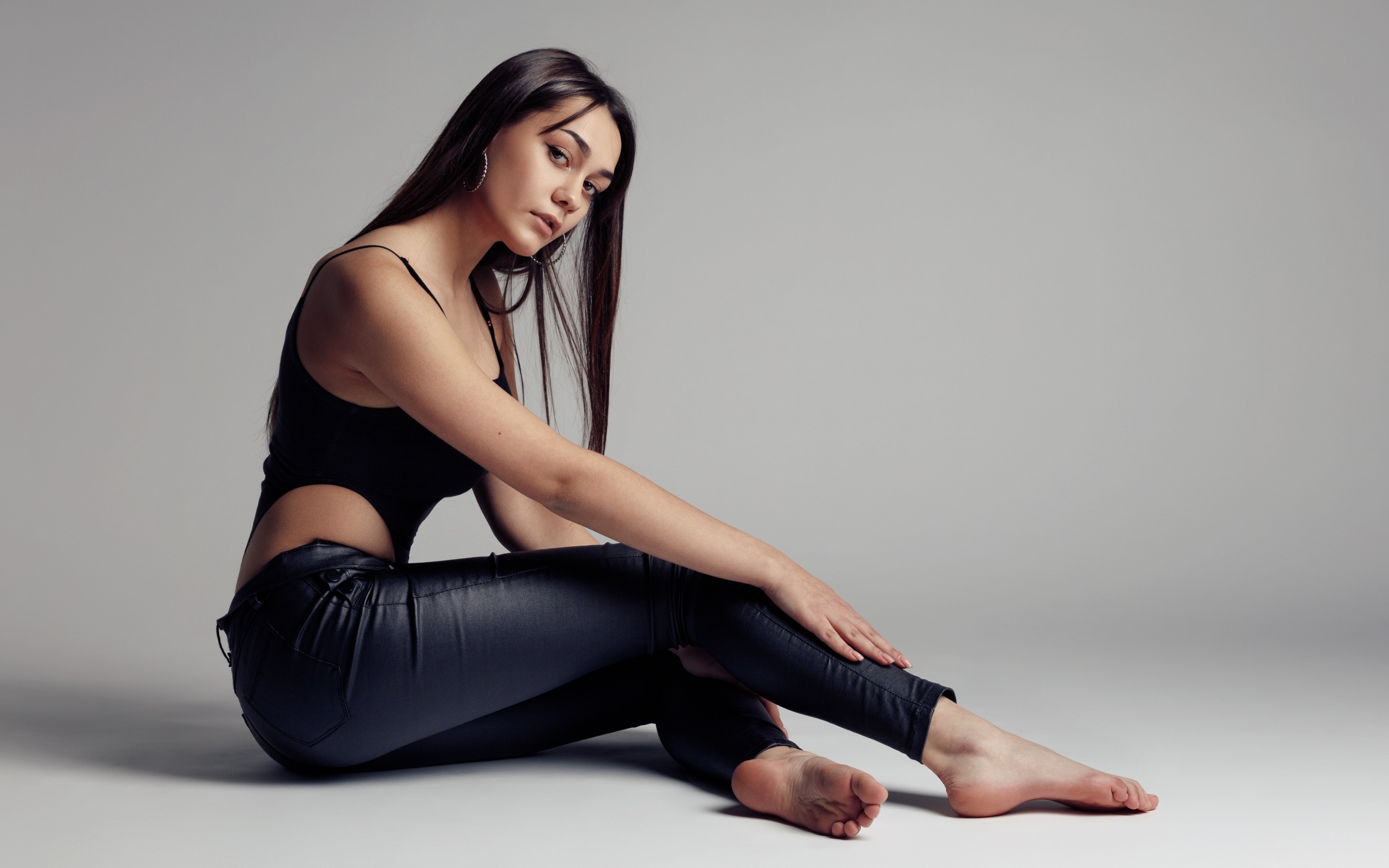 Красивая девушка в черных брюках на сером фоне
