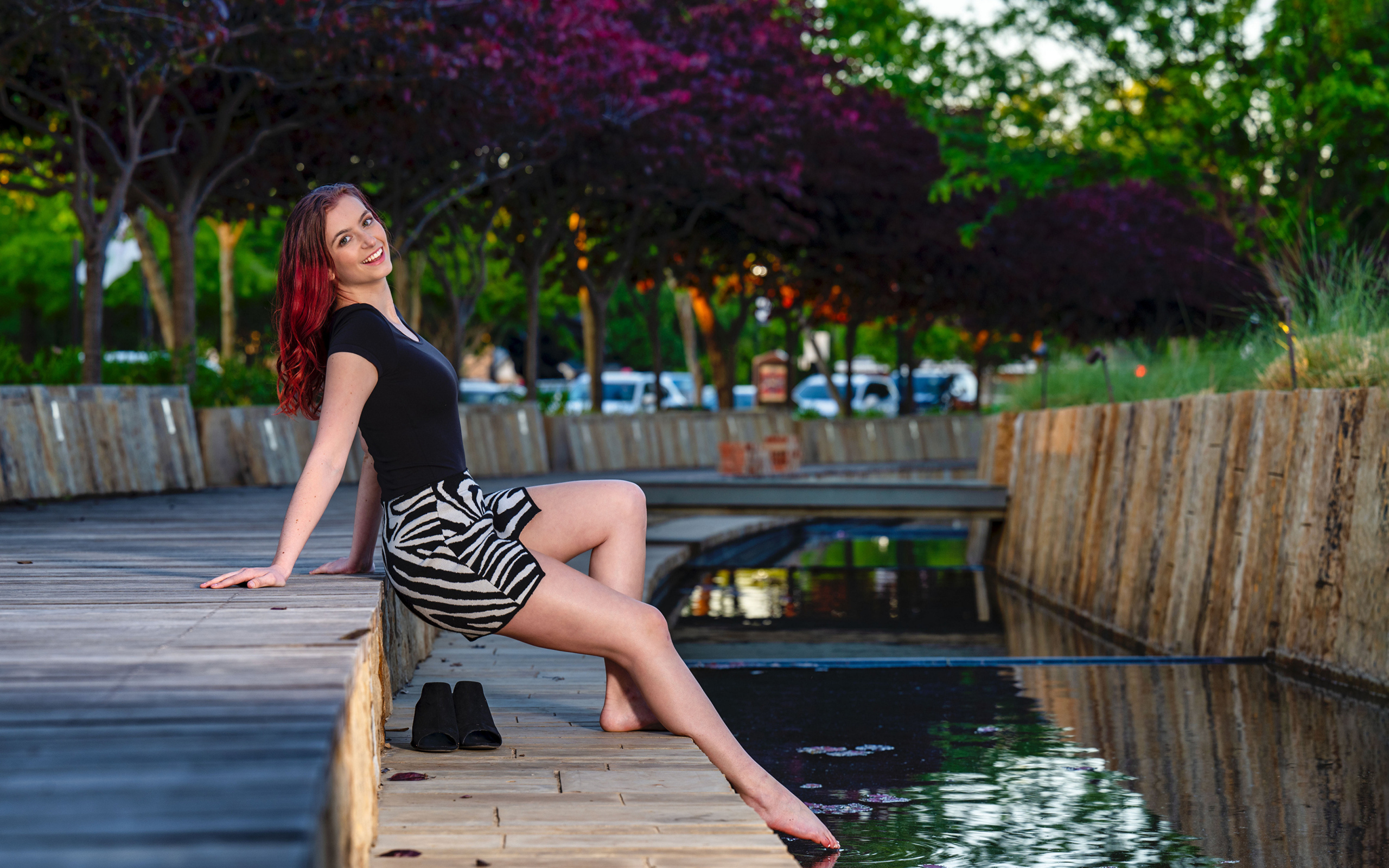 Красивая девушка опустила ноги в воду