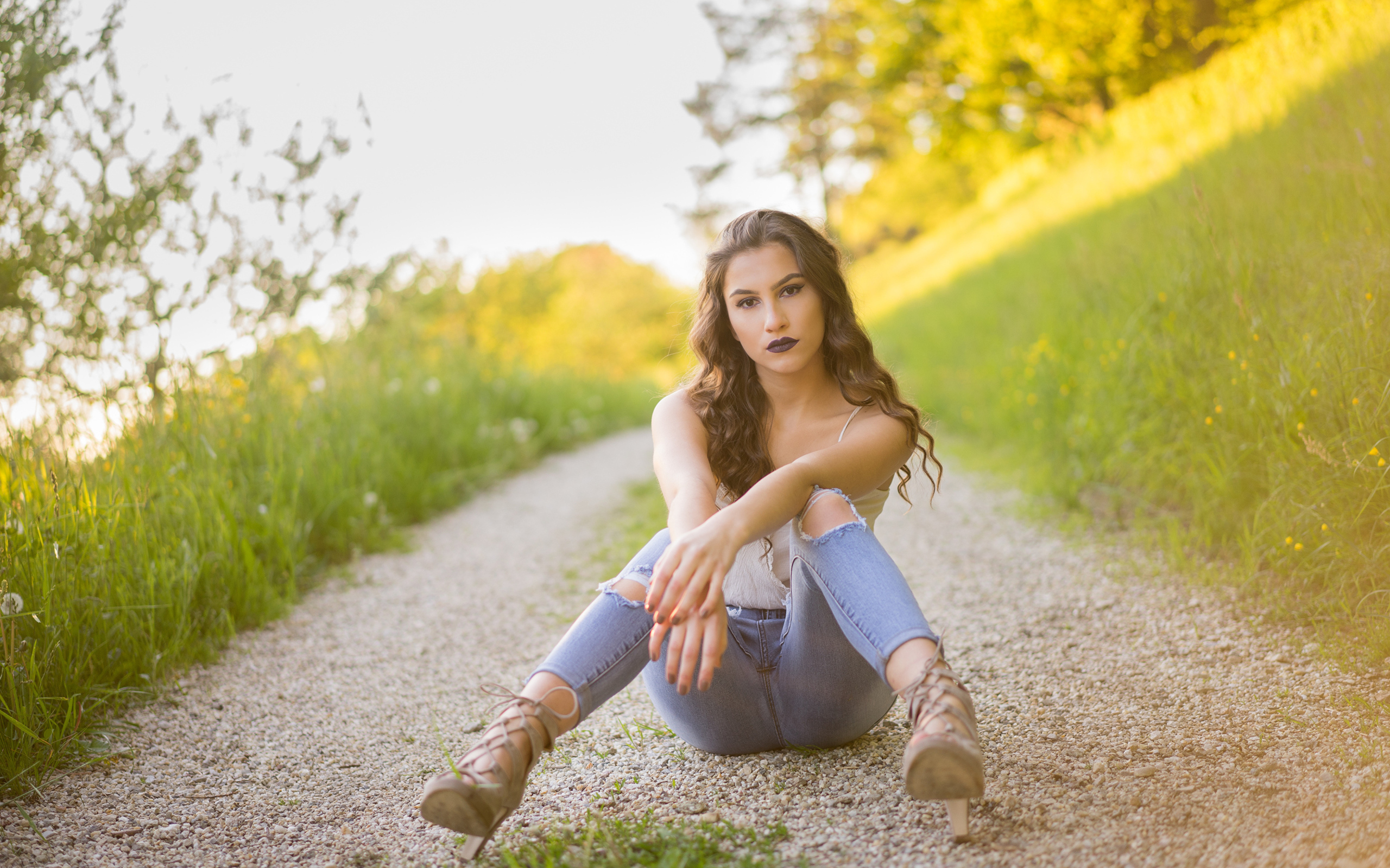 Красивая девушка сидит на дороге летом