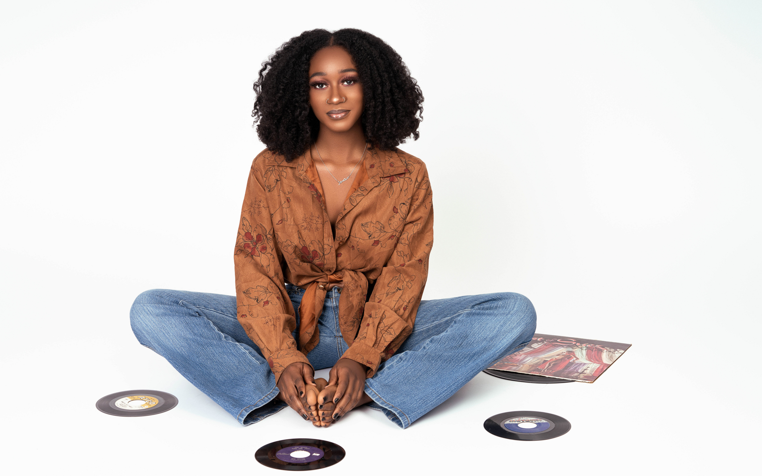 Темнокожая девушка сидит на белом фоне с пластинками