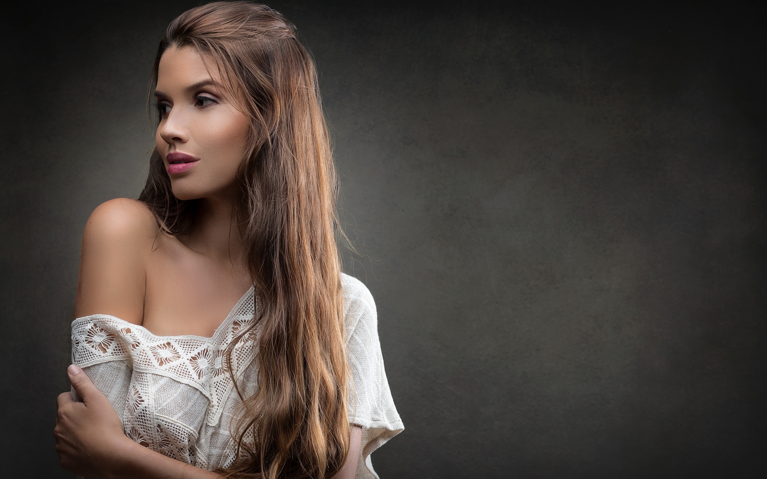 Девушка в белом платье с длинными волосами на сером фоне