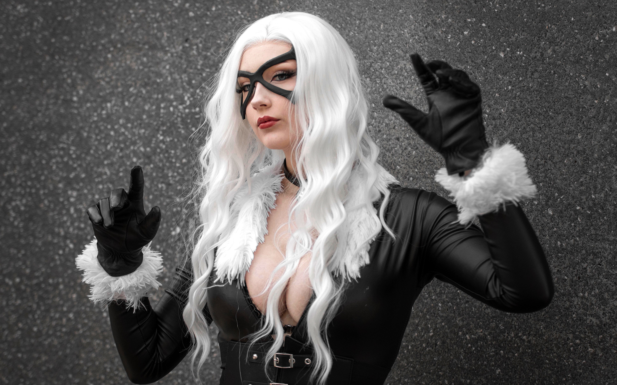 Девушка в белом парике в черном костюме у серой стены