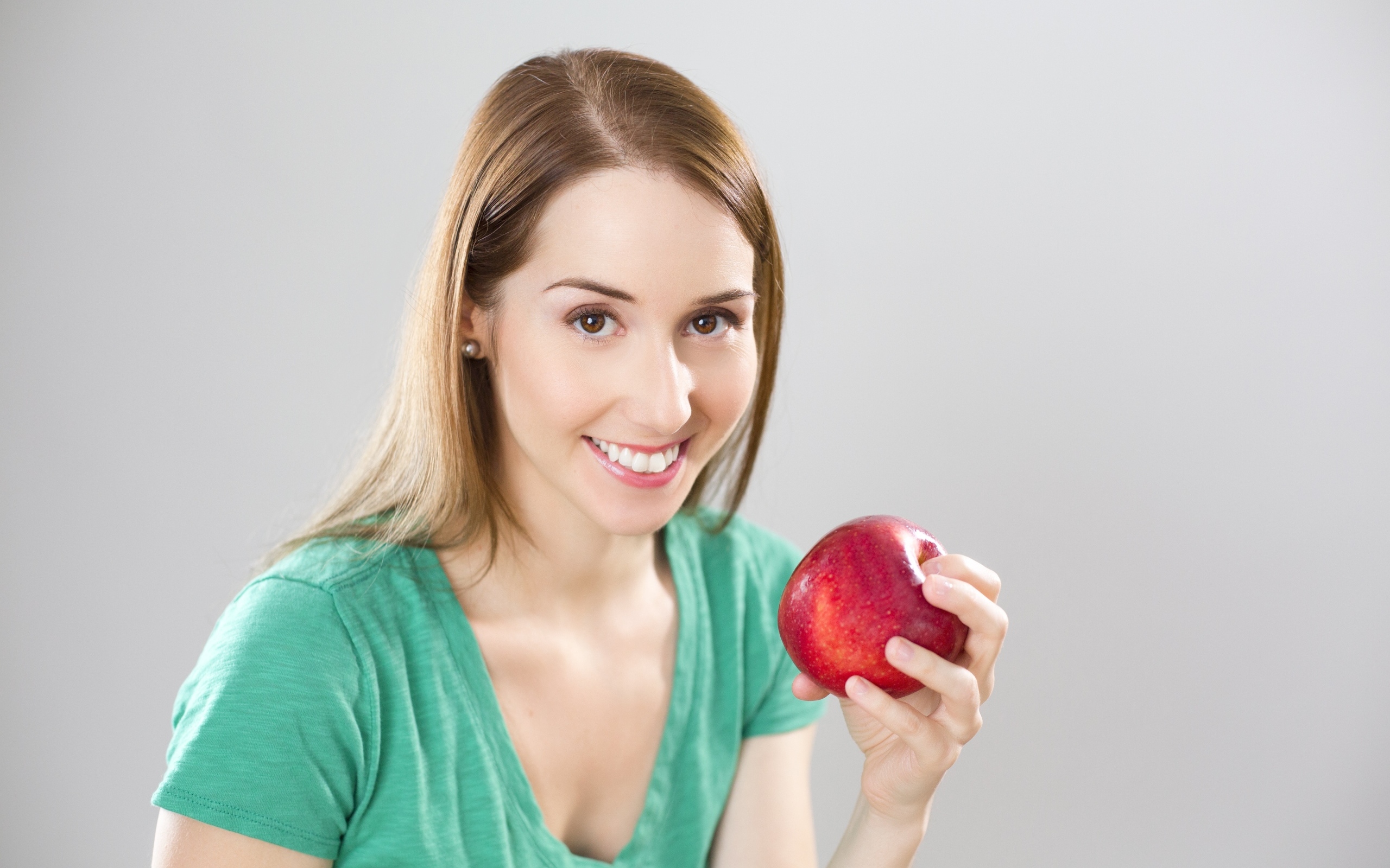 Улыбающаяся девушка с красным яблоком в руках