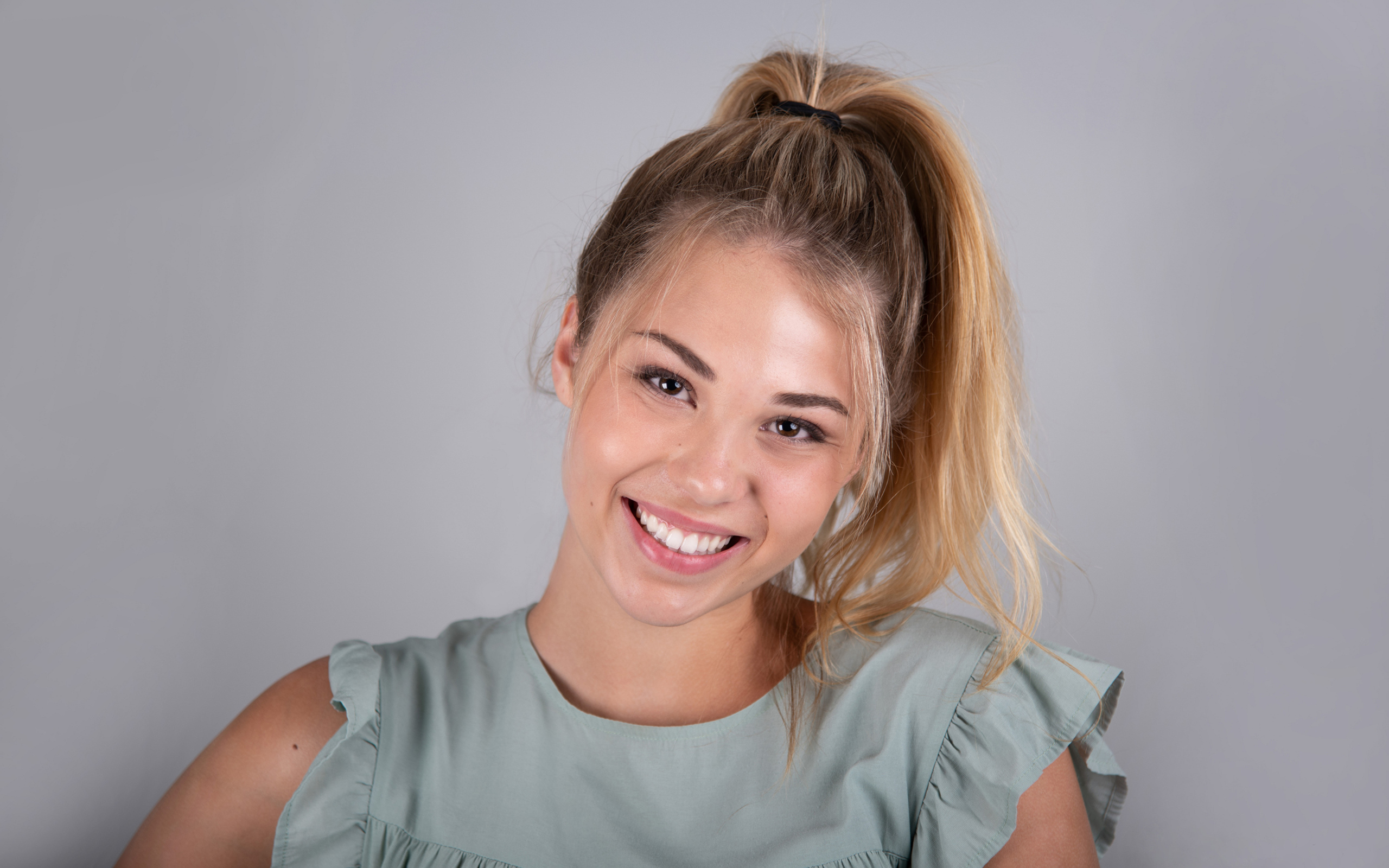 Молодая девушка блондинка на сером фоне
