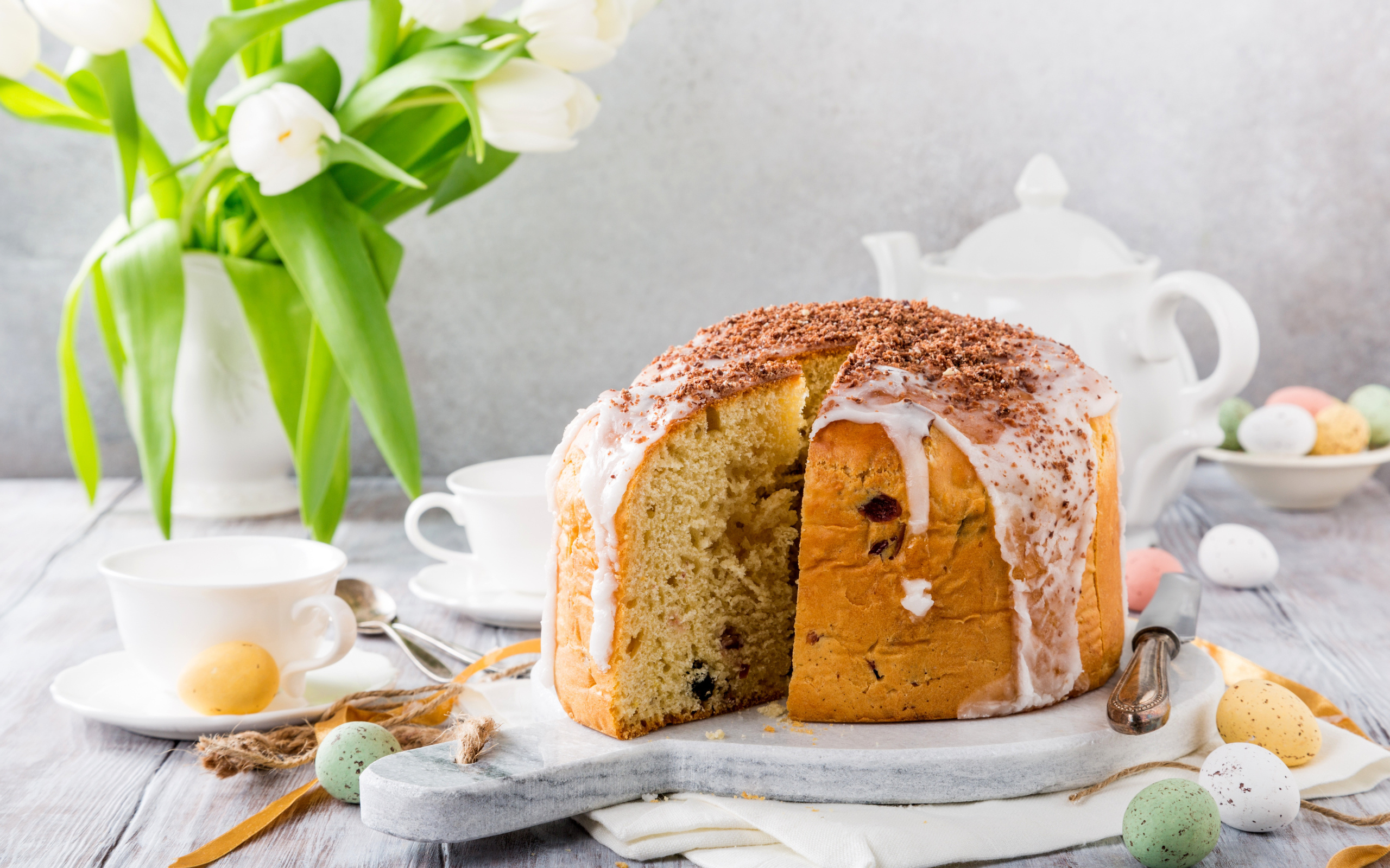 Пасхальный кулич на столе с букетом тюльпанов и сладостями