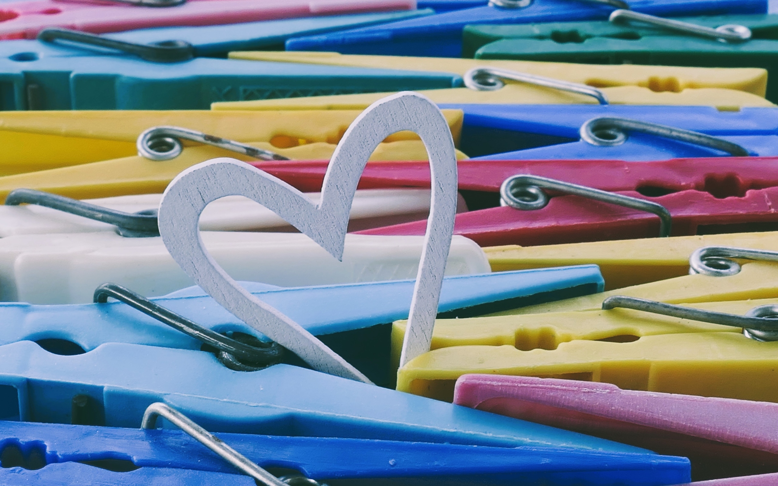 Белое деревянное сердце с разноцветными прищепками