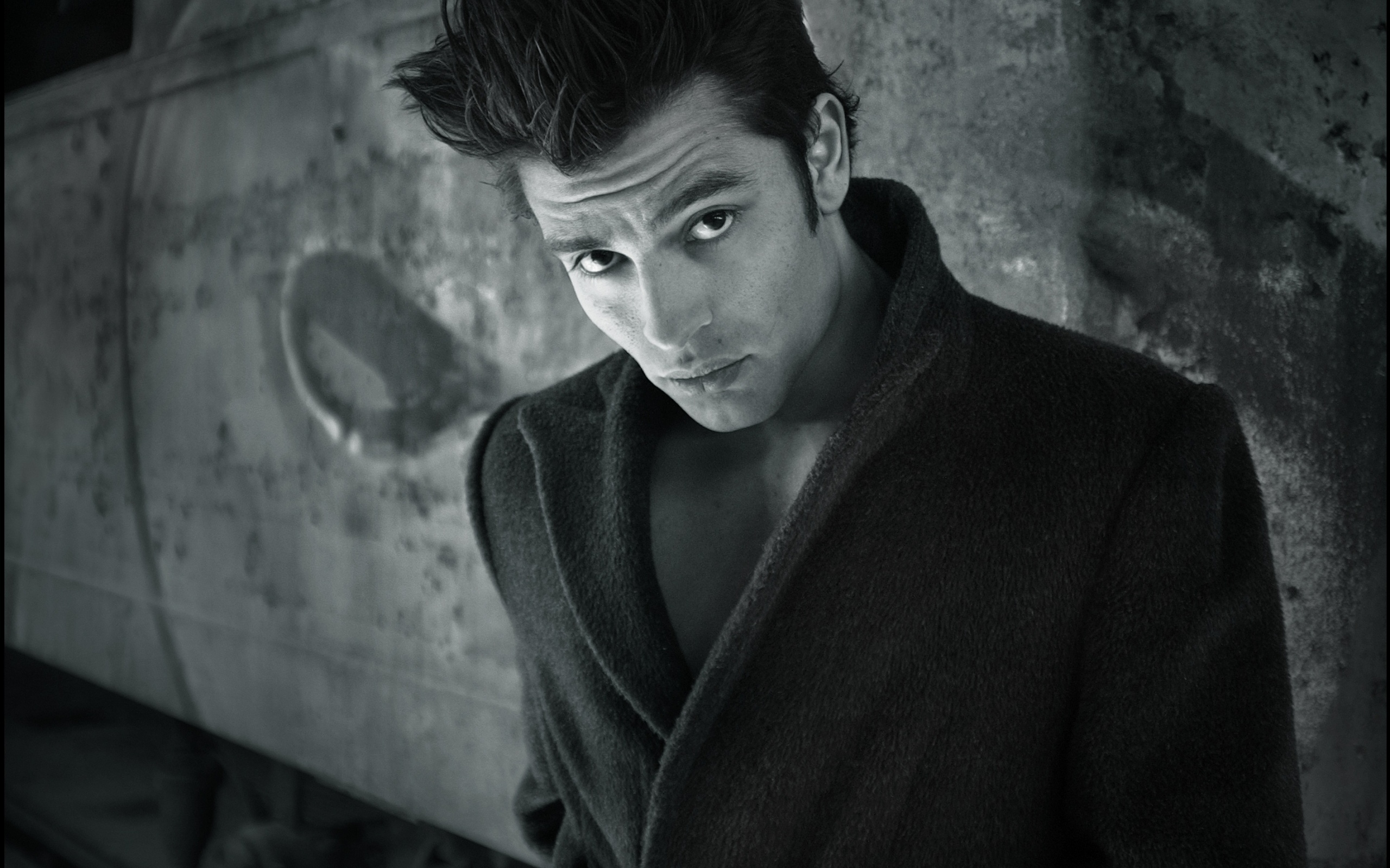 Красивый мужчина в черном пальто у стены