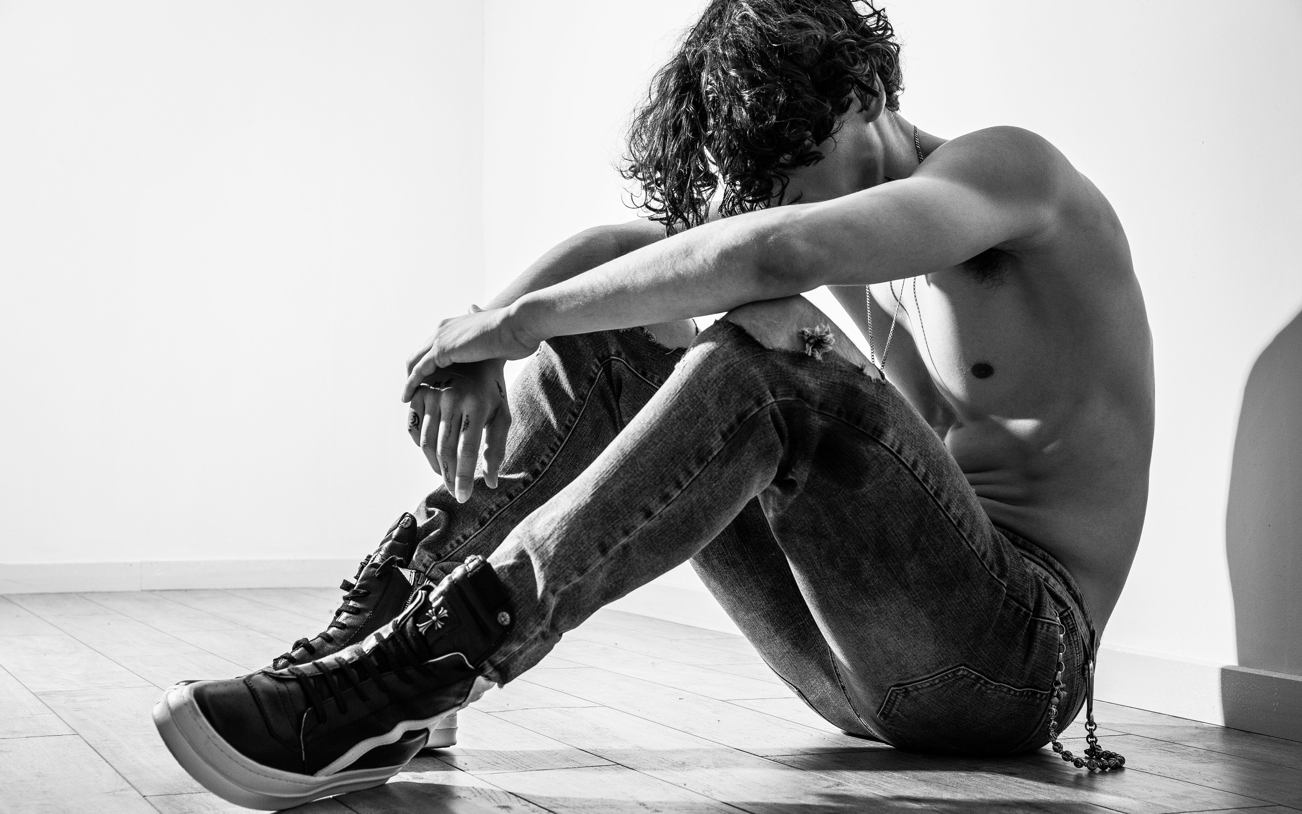 Грустный мужчина в джинсах сидит на полу