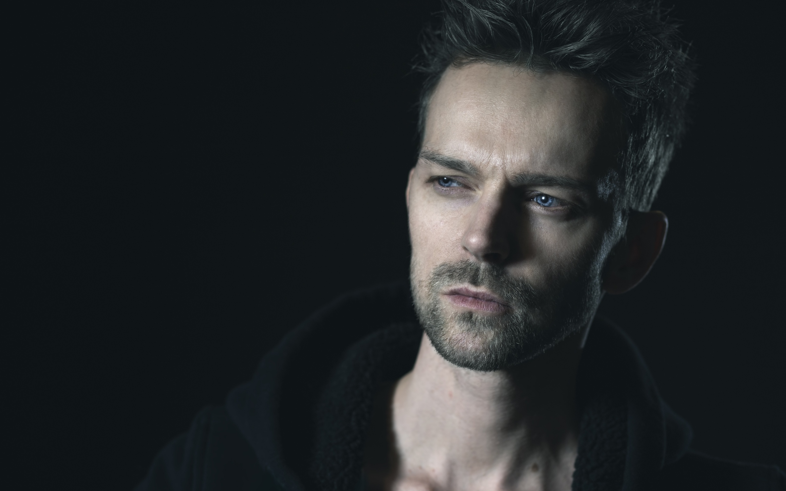 Серьезный голубоглазый мужчина на черном фоне