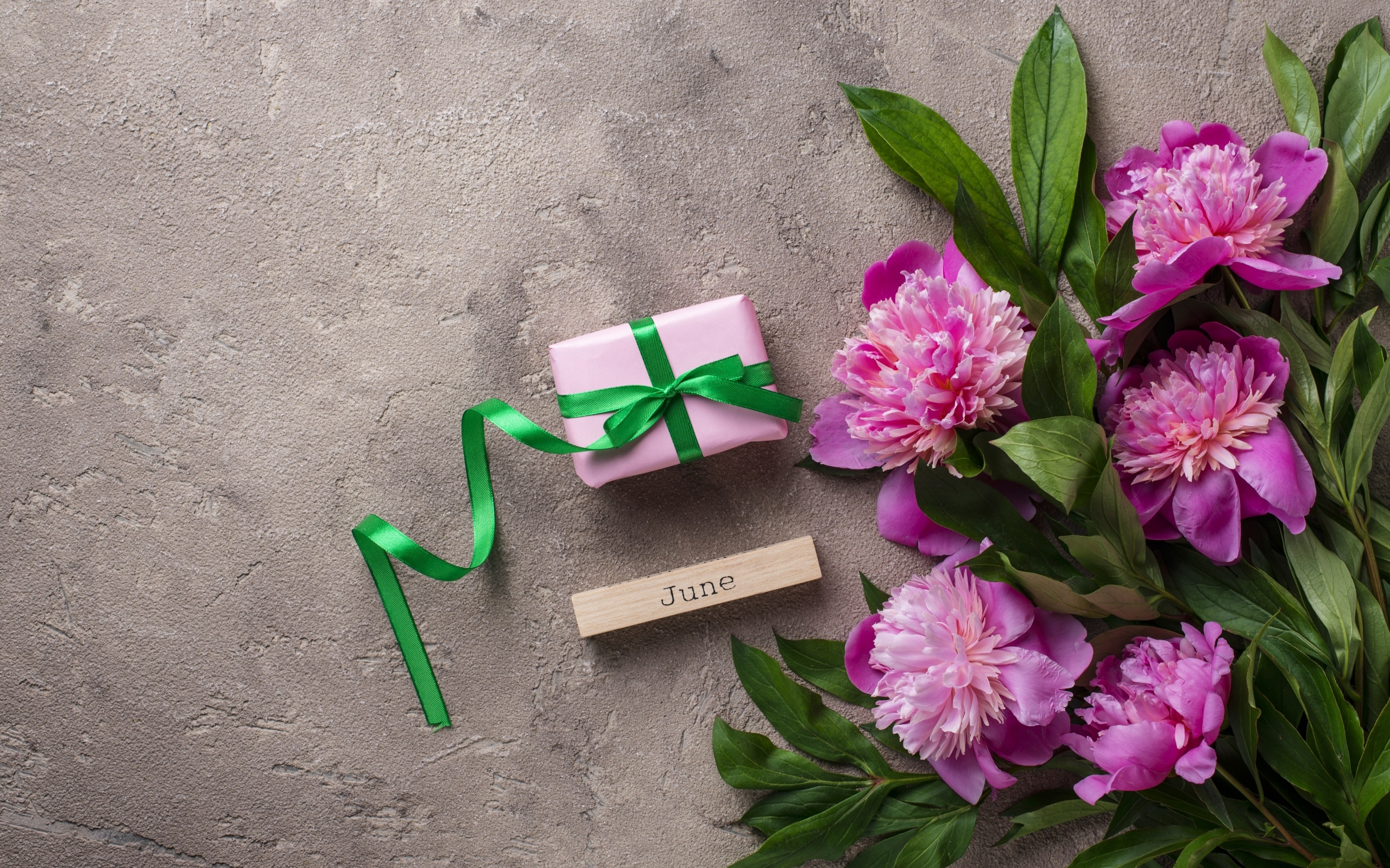 Букет розовых пионов с подарком на сером столе