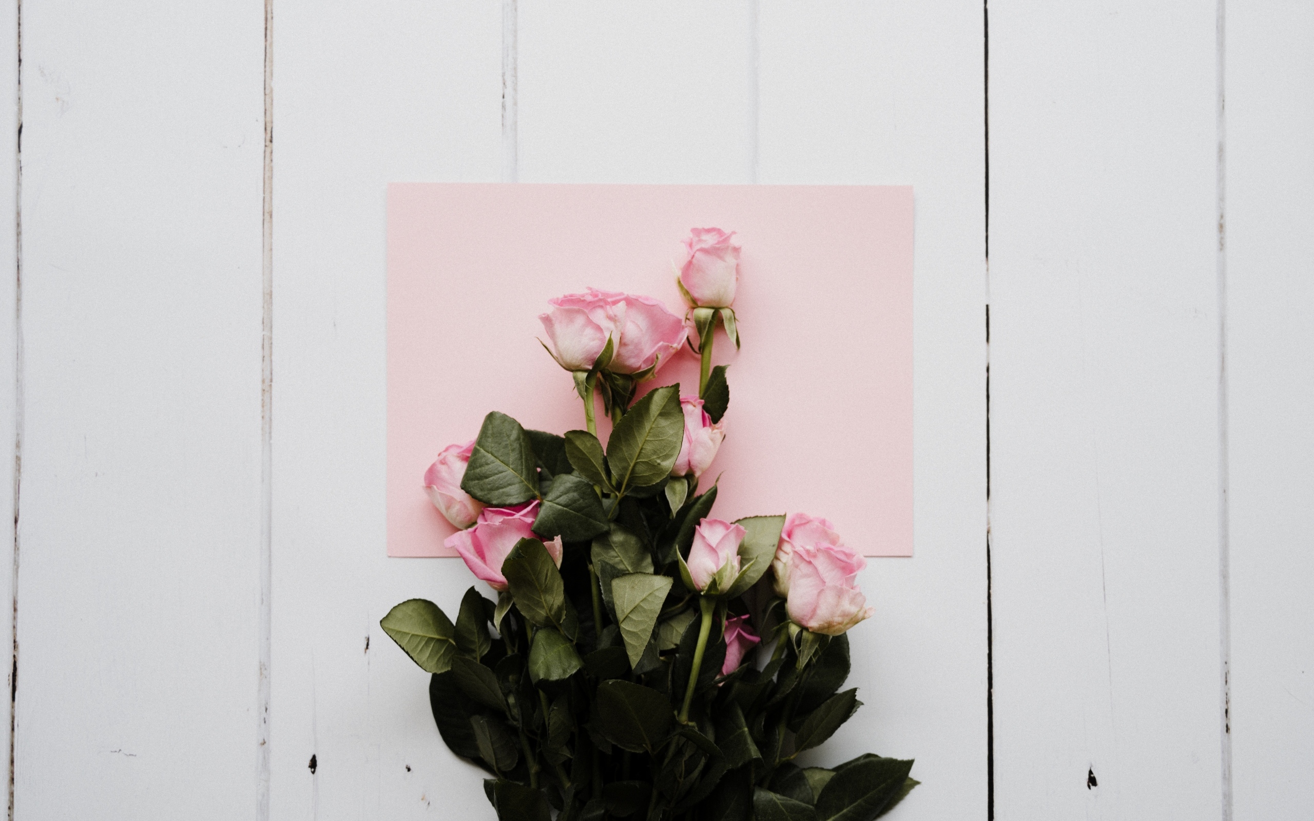 Букет роз с розовым листом бумаги на столе