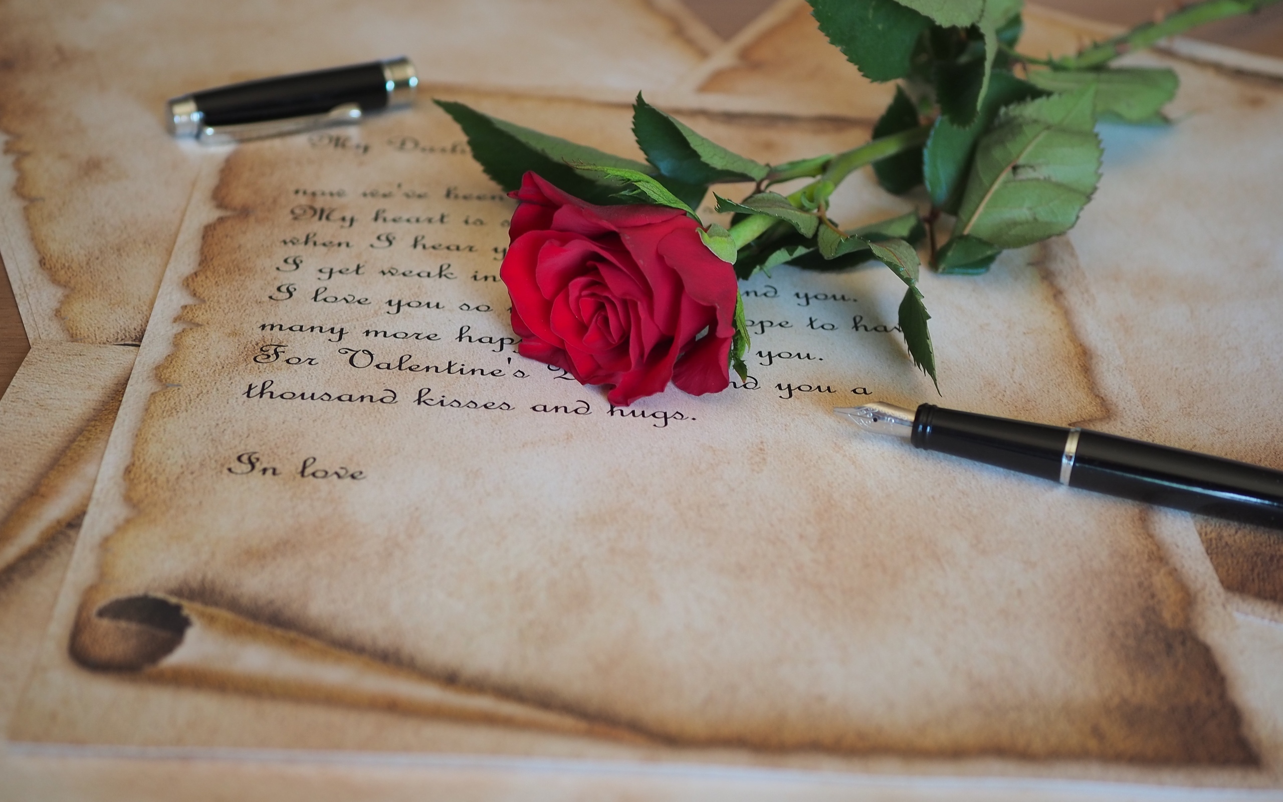 Красная роза с запиской и ручкой на столе
