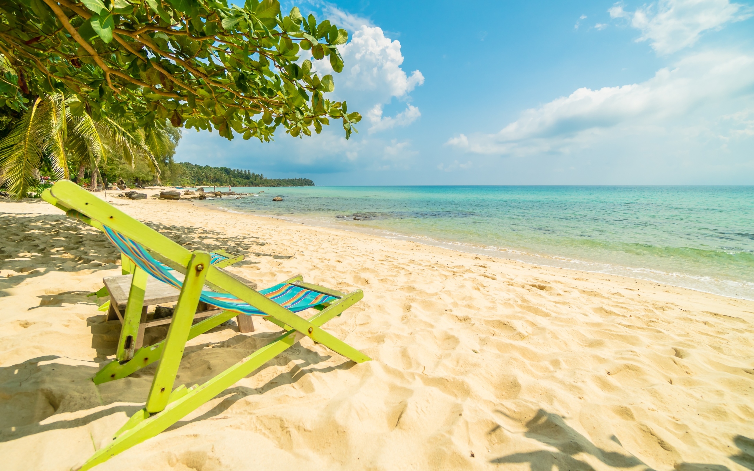 Шезлонг стоит на горячем песке у моря летом