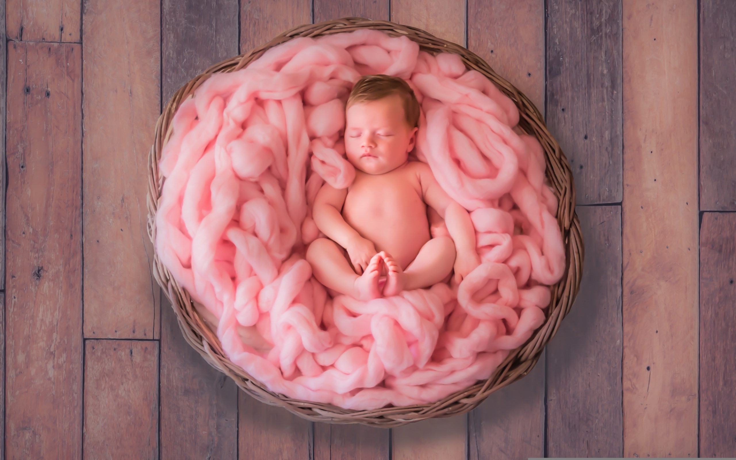 Ребенок спит в корзине с розовым покрывалом