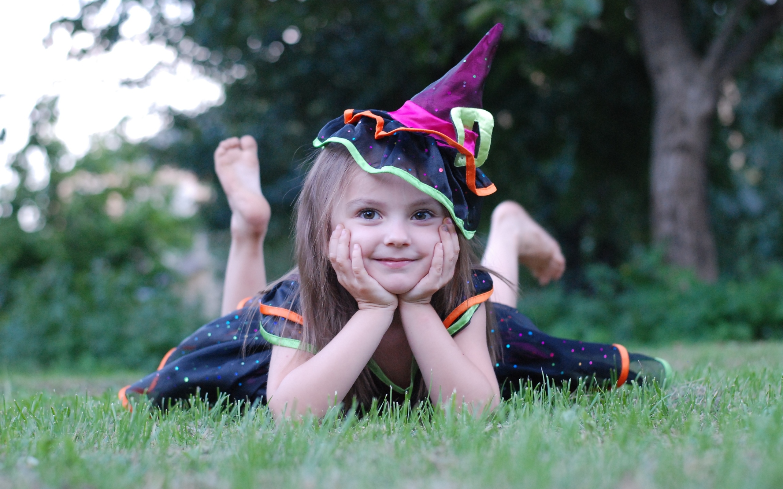 Девочка в костюме лежит на зеленой траве