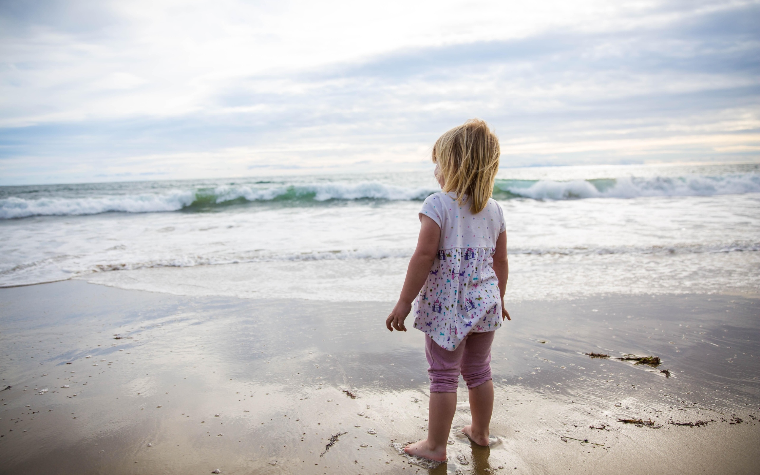 Маленькая девочка стоит на берегу моря