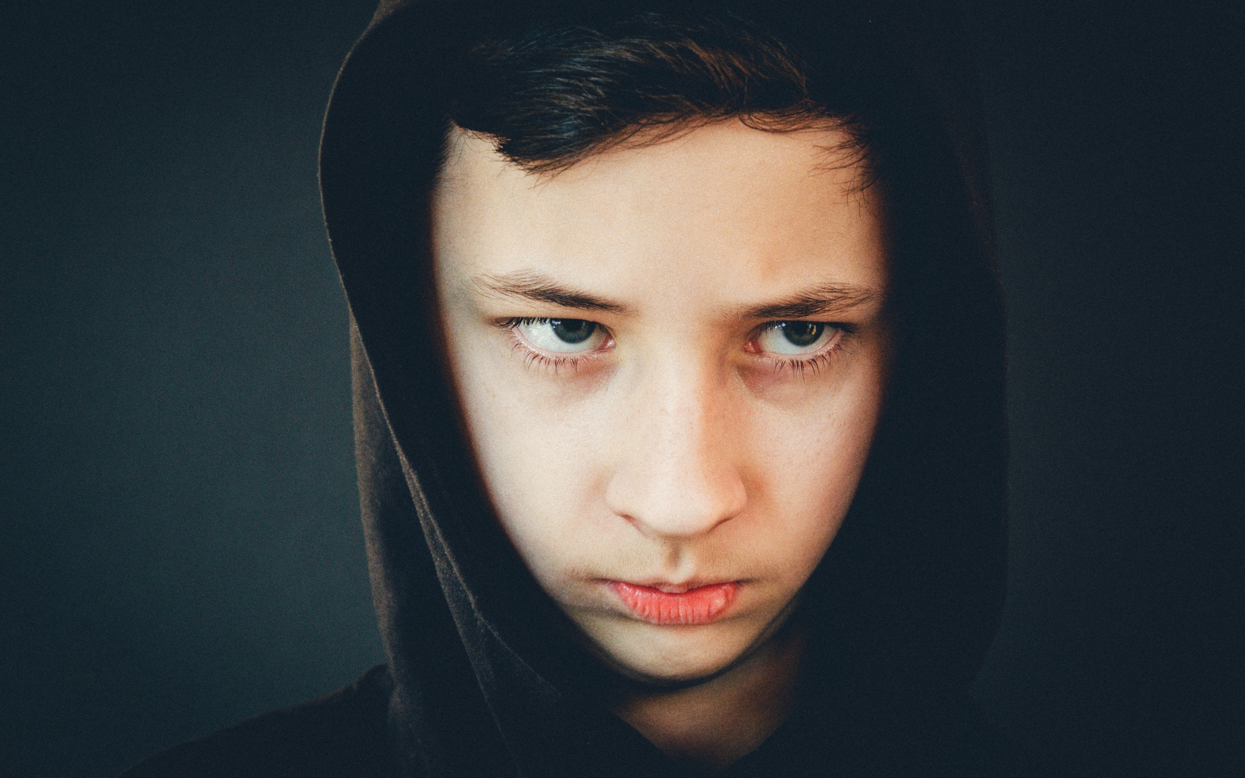 Серьезный мальчик в черном капюшоне