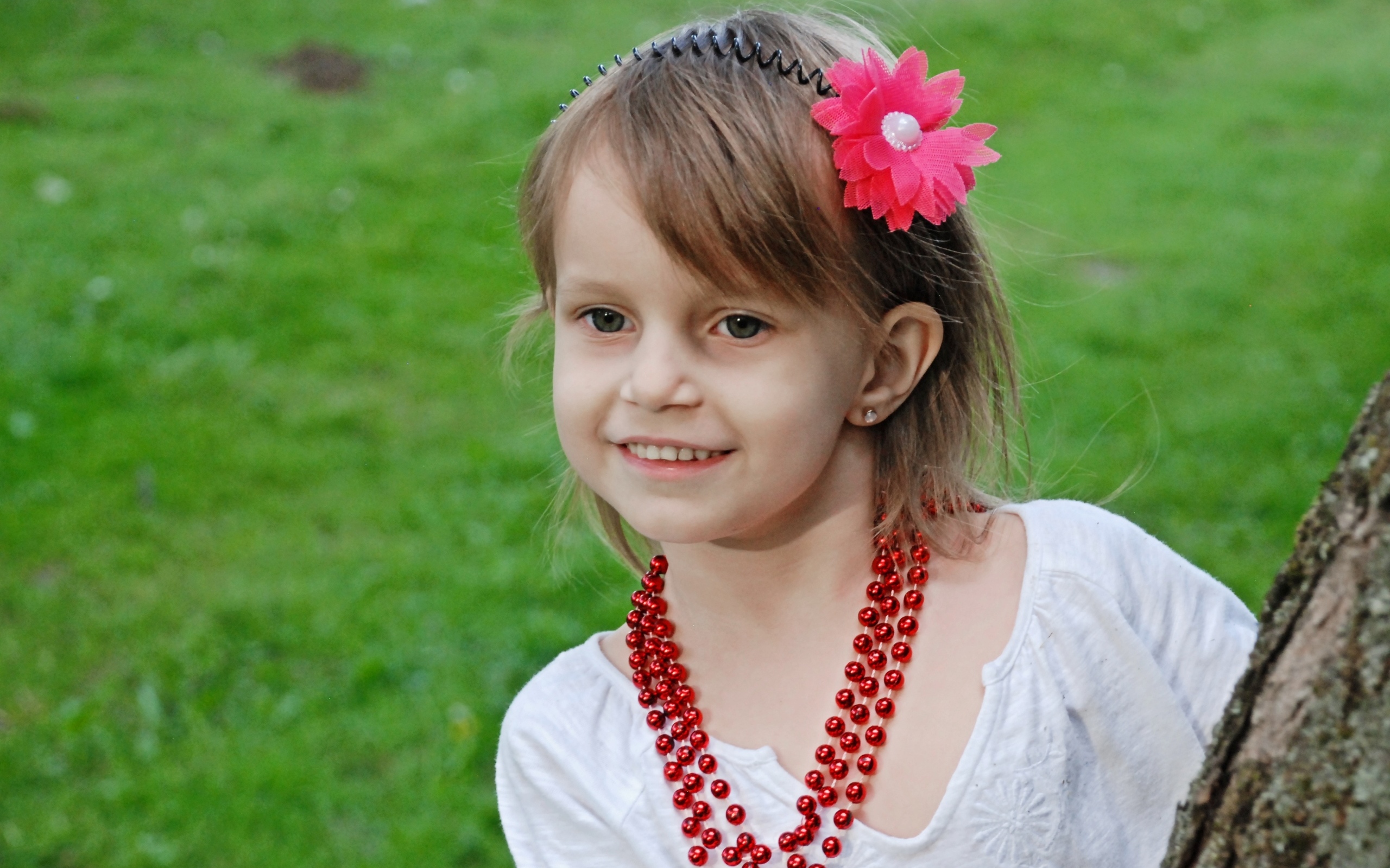 Улыбающаяся девочка стоит у дерева