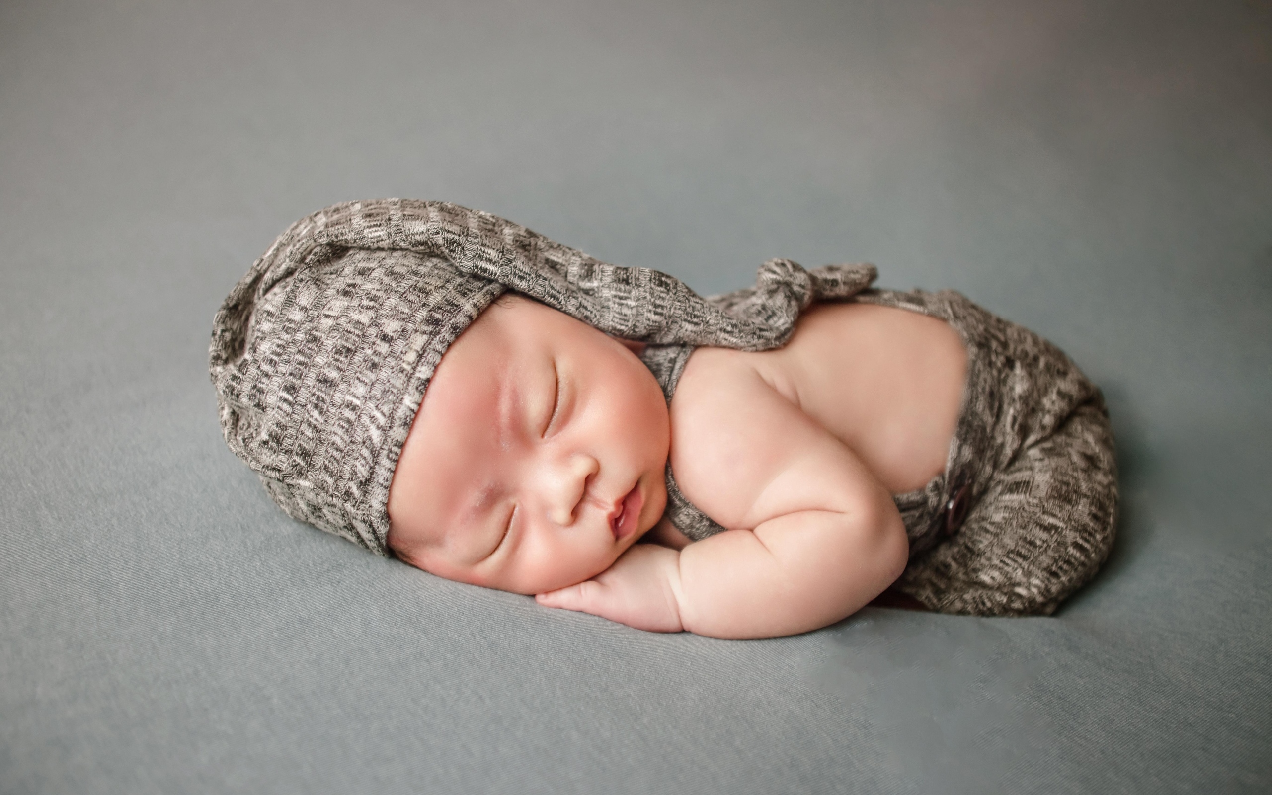 Ребенок спит в костюме на сером покрывале