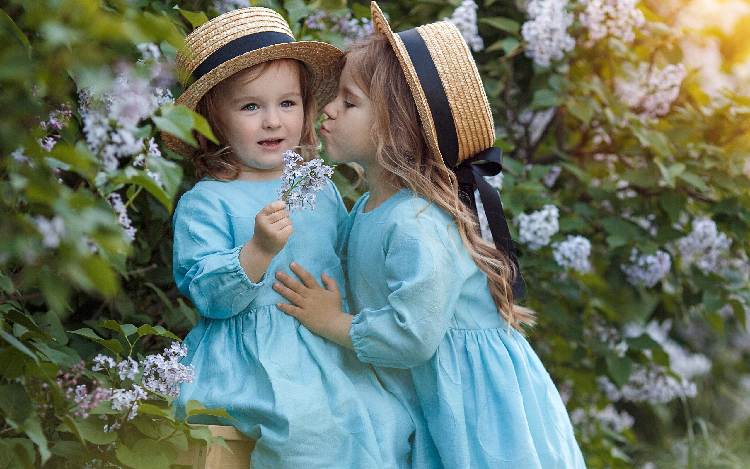 Две маленькие девочки в саду с сиренью