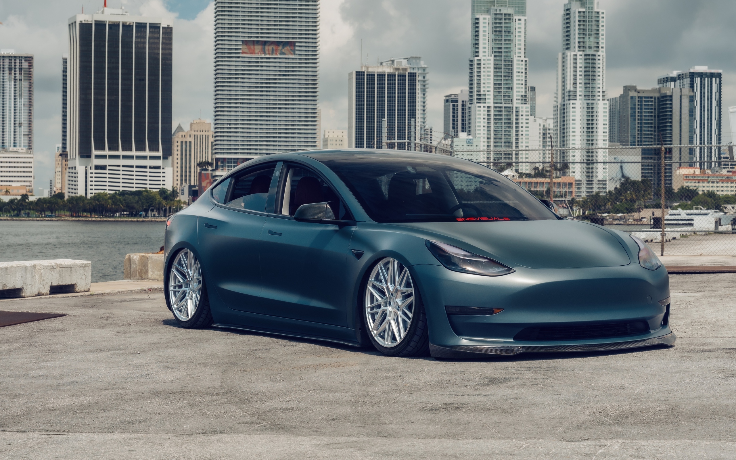 Электрокар Tesla Model 3 на фоне небоскребов